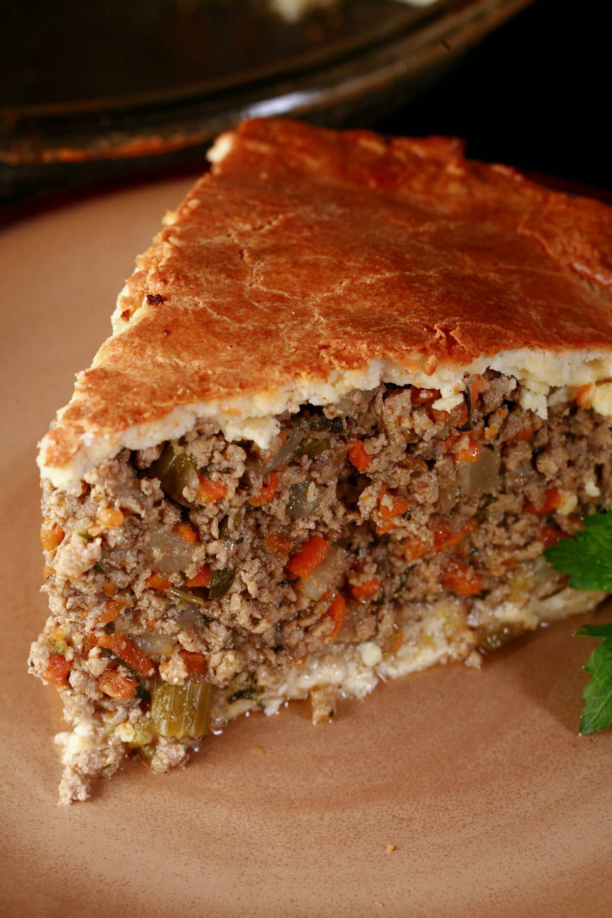A close up photo of a tall slice of keto tourtiere.