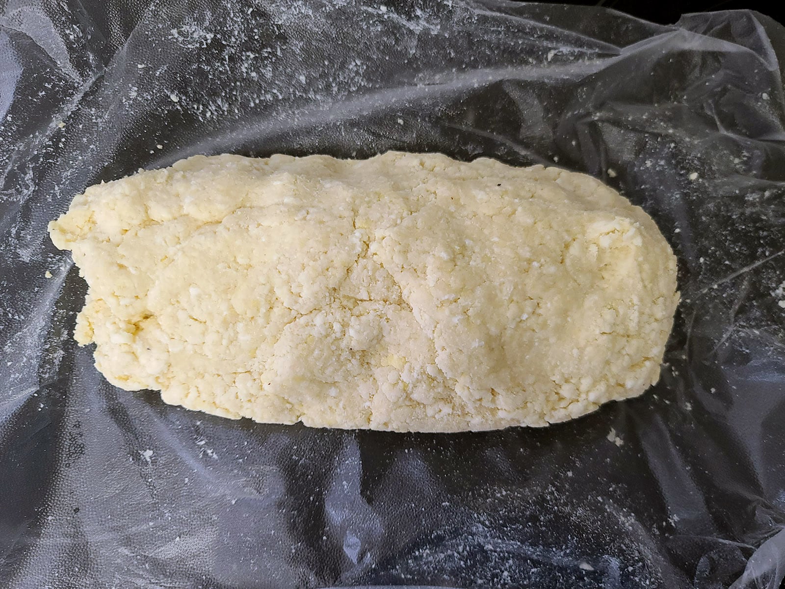 A log of keto pie dough on a piece of plastic wrap.