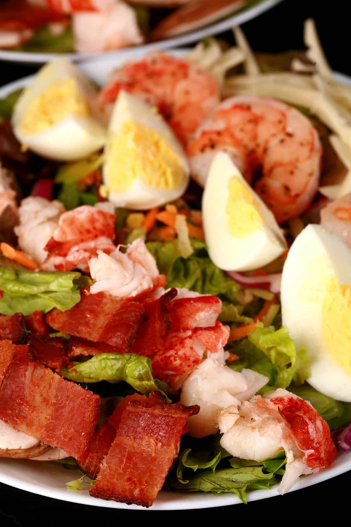 A seafood cobb salad, with shrimp and lobster laid out in rows with boiled eggs and other ingredients.