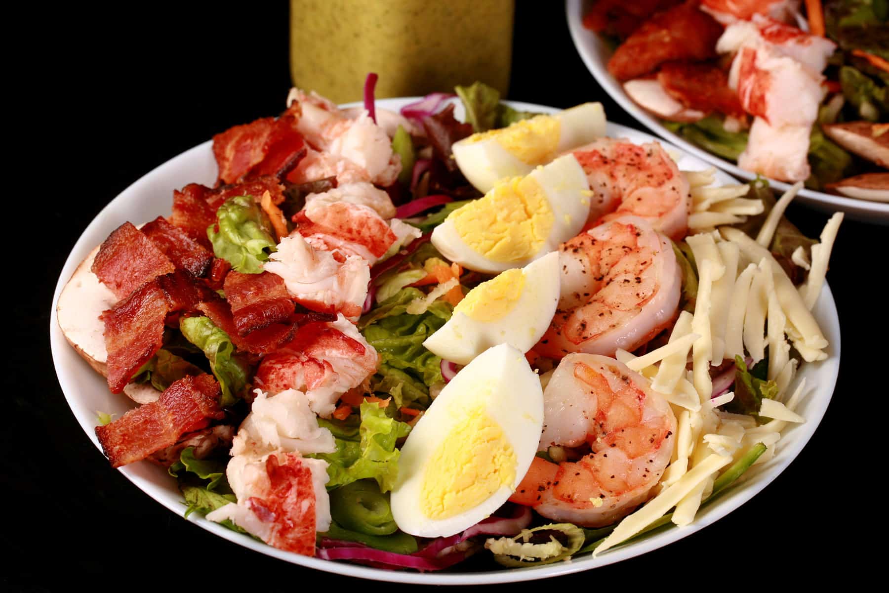 A seafood cobb salad with a bottle of lemon dill vinaigrette.