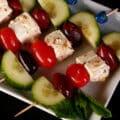A tray of Greek Salad Appetizer Skewers with cucumbers, tomatoes, kalamata olives, and marinated feta cheese.
