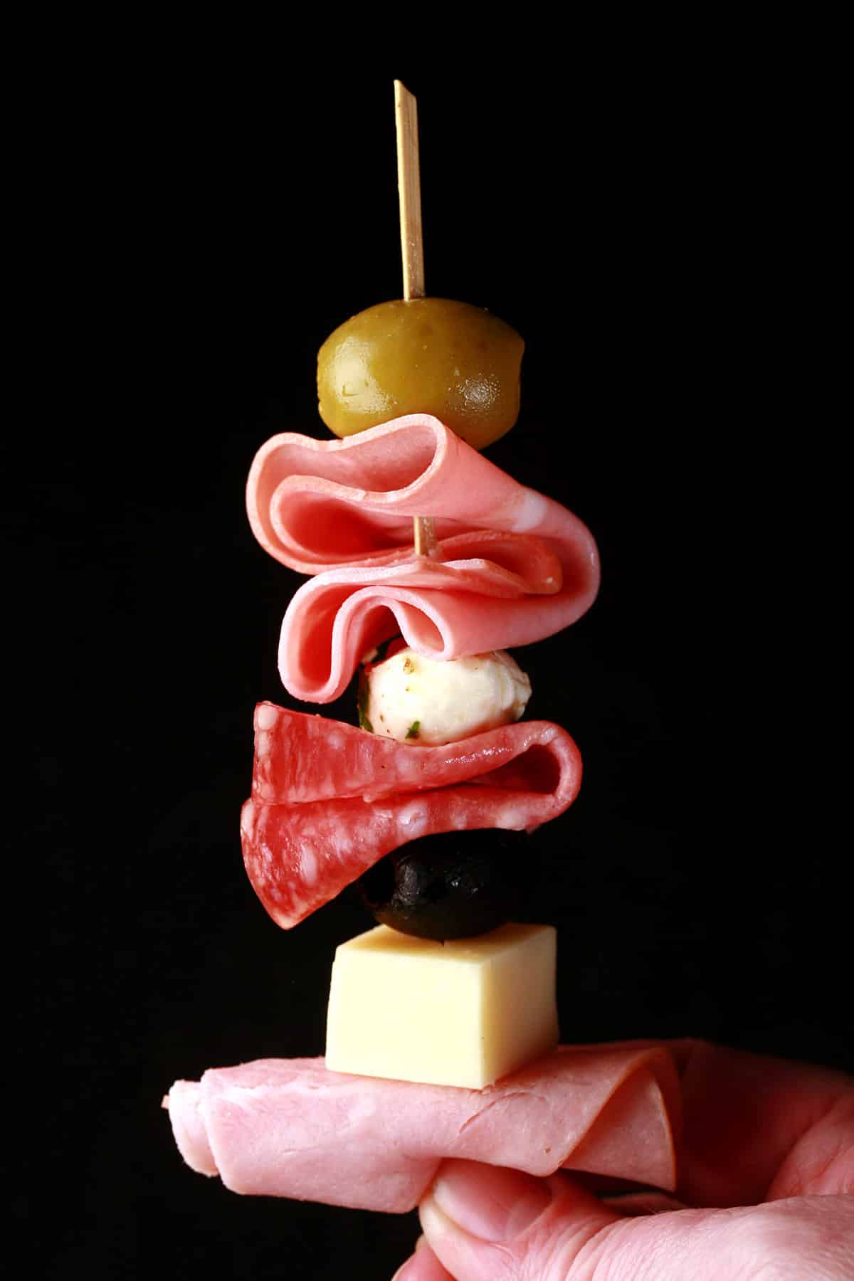 A single muffuletta skewer with meats, cheeses, and olives.