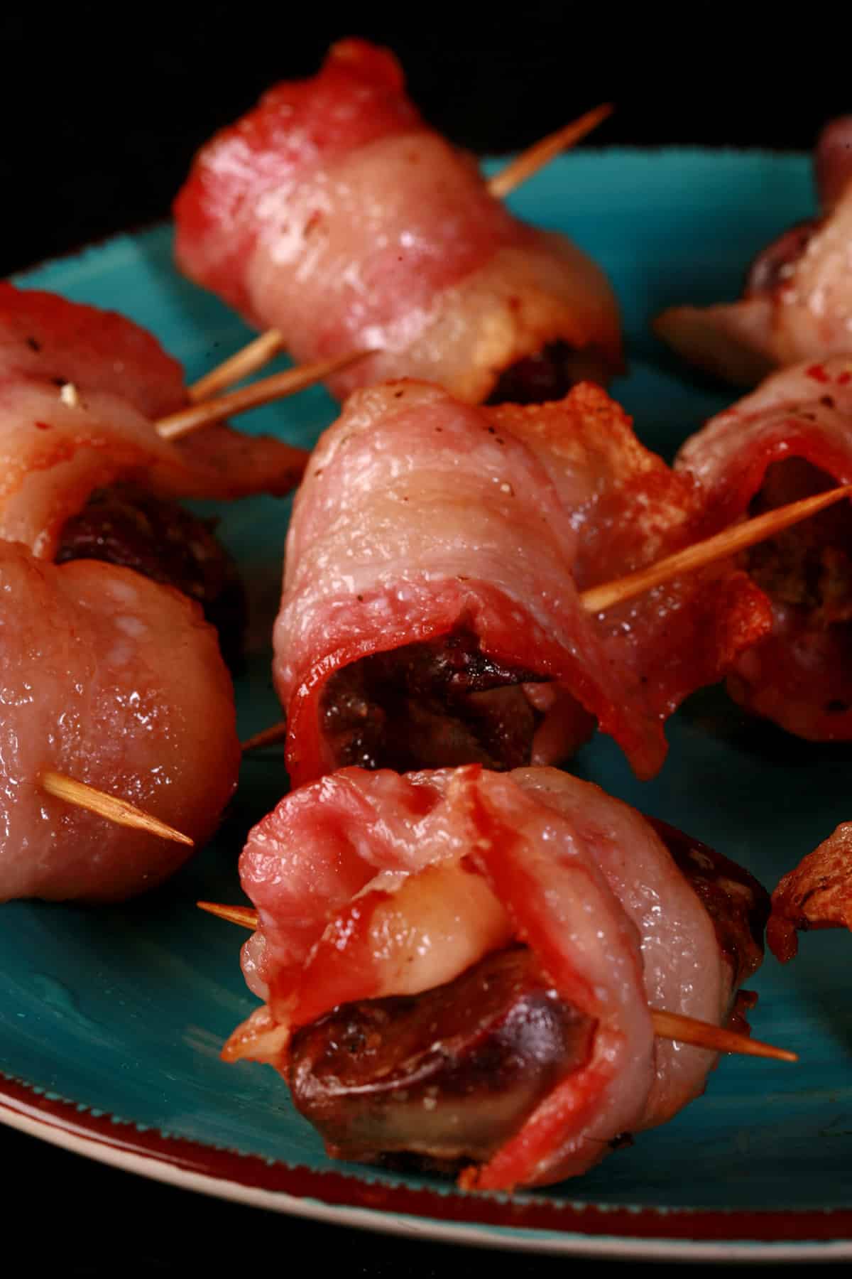 A plate of bacon wrapped chicken livers, each speared with a toothpick.