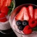 2 glasses of berry protein pudding, topped with strawberry slices, raspberries, and blueberries.
