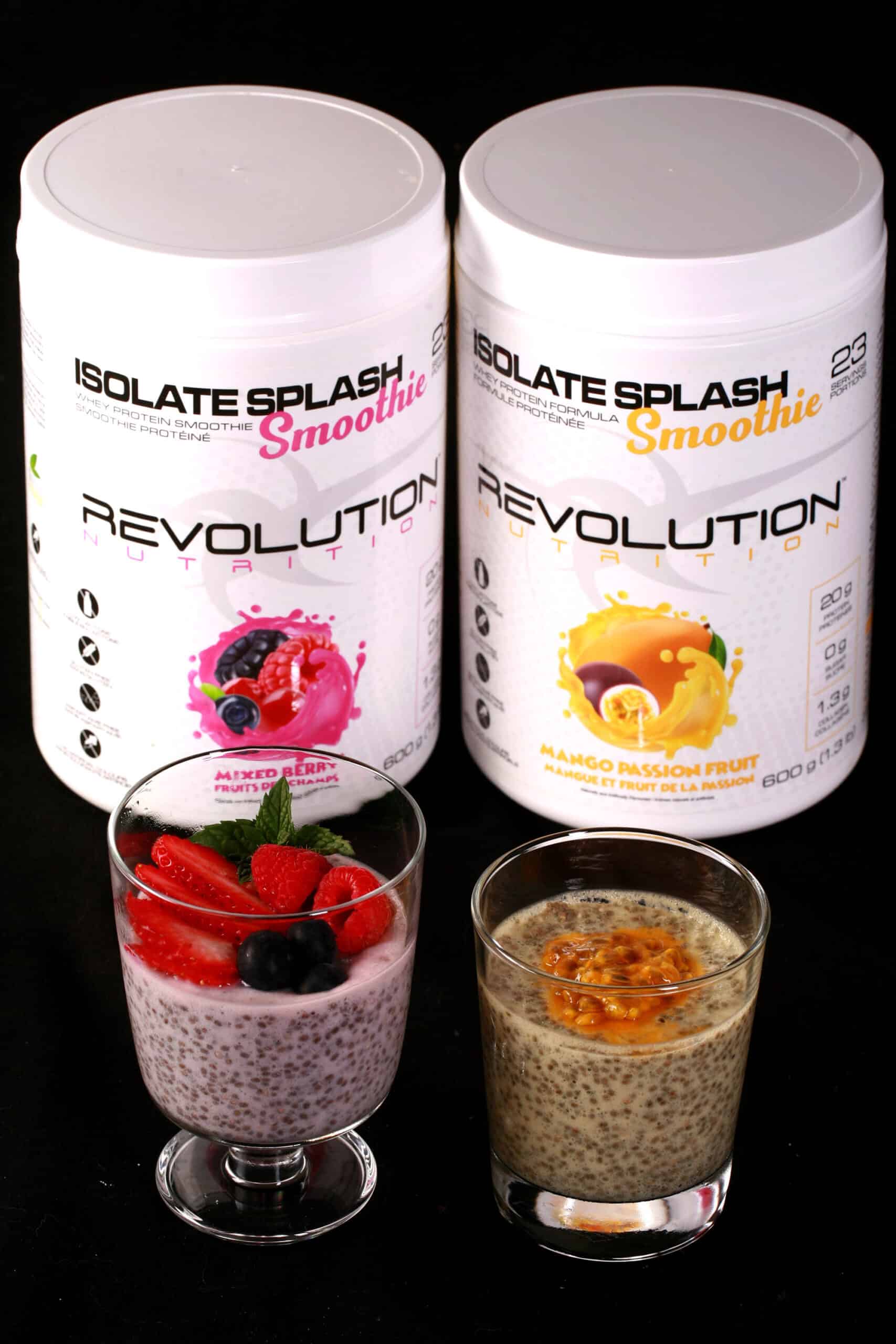 2 canisters of revolution nutrition isolate splash smoothie powder, with 2 glasses of fruit topped protein chia pudding in front.