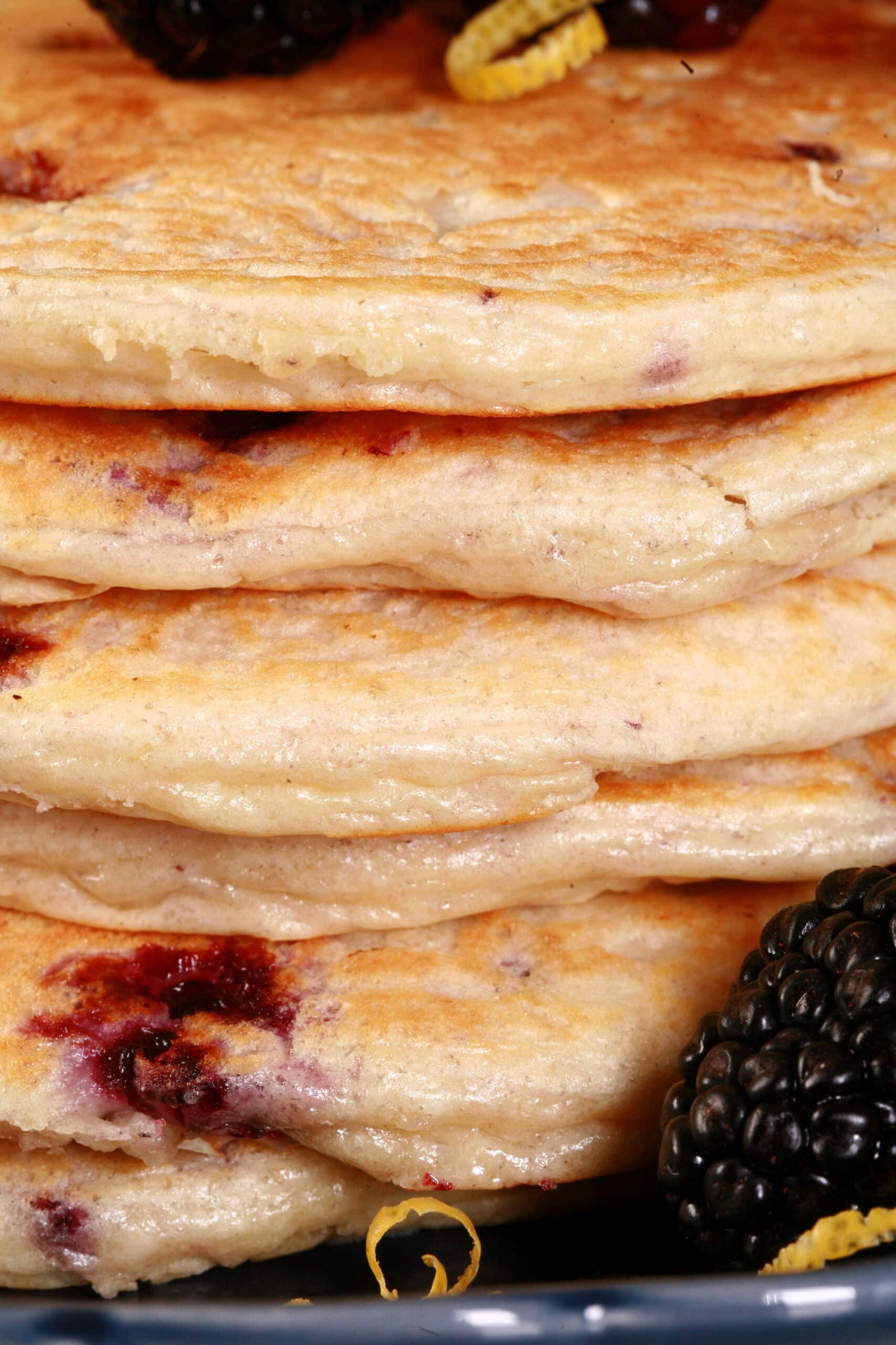A stack of 6 blackberry protein pancakes with blackberries.