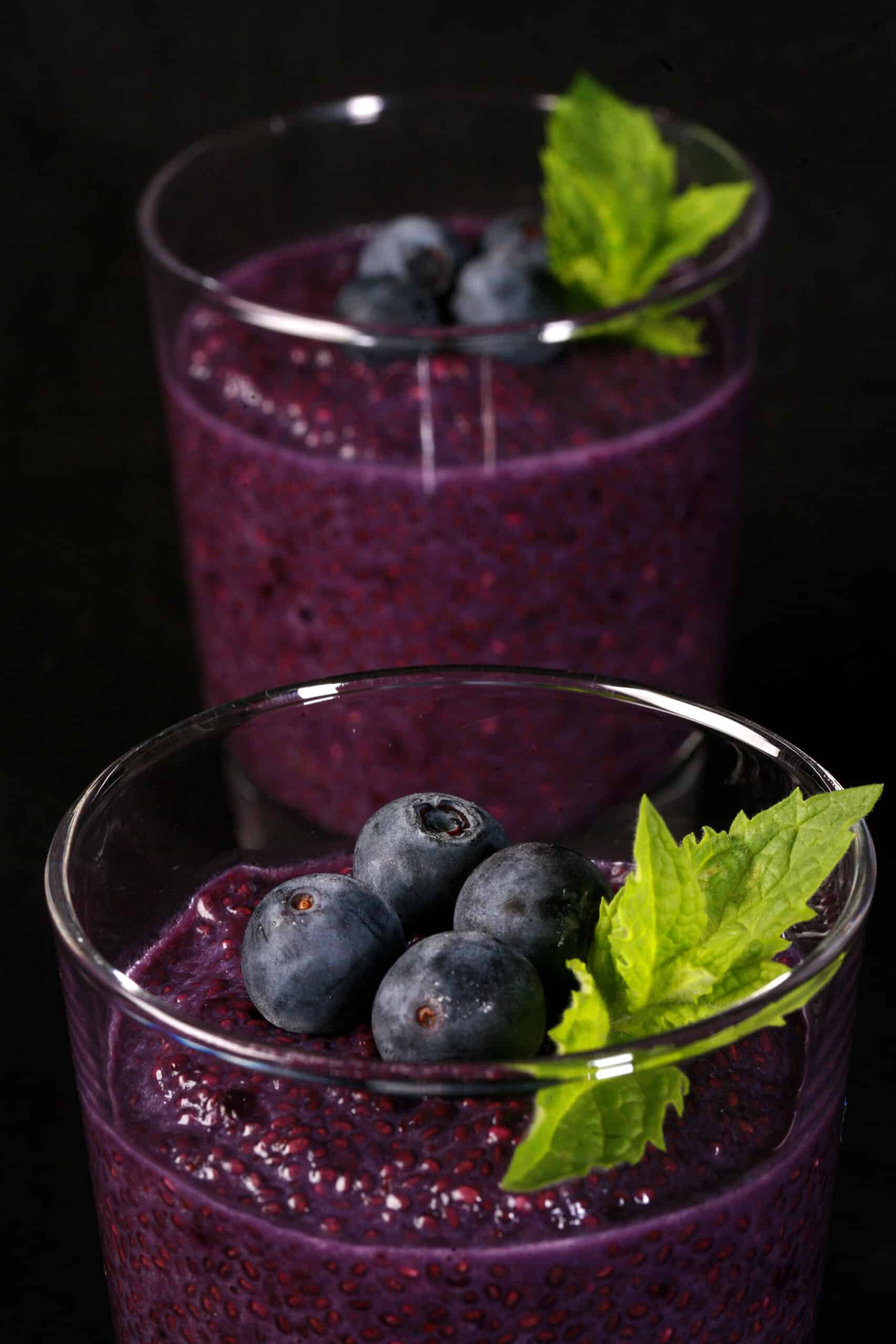 2 blueberry chia puddings, each topped with fresh blueberries and a mint sprig.