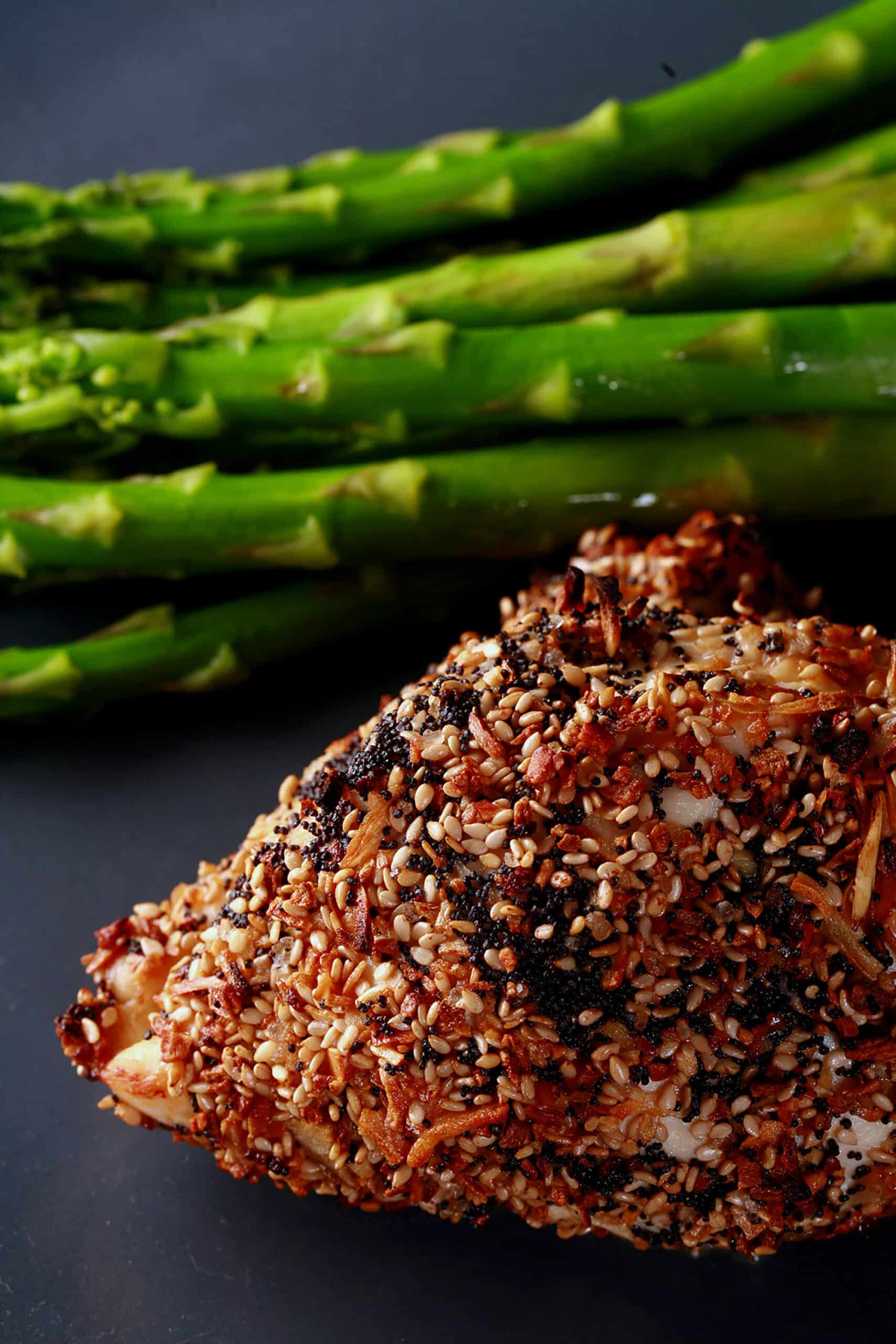 A roasted cream cheese stuffed everything chicken breast on a plate with some asparagus.