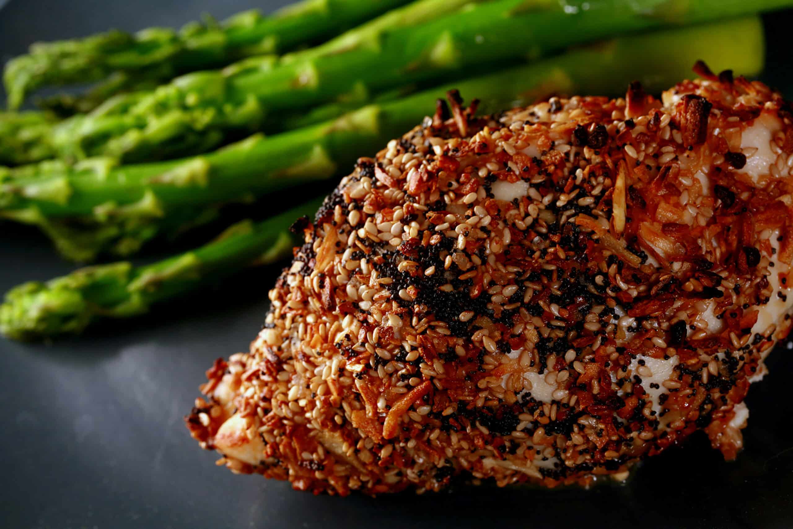 A roasted cream cheese stuffed everything chicken breast on a plate with some asparagus.
