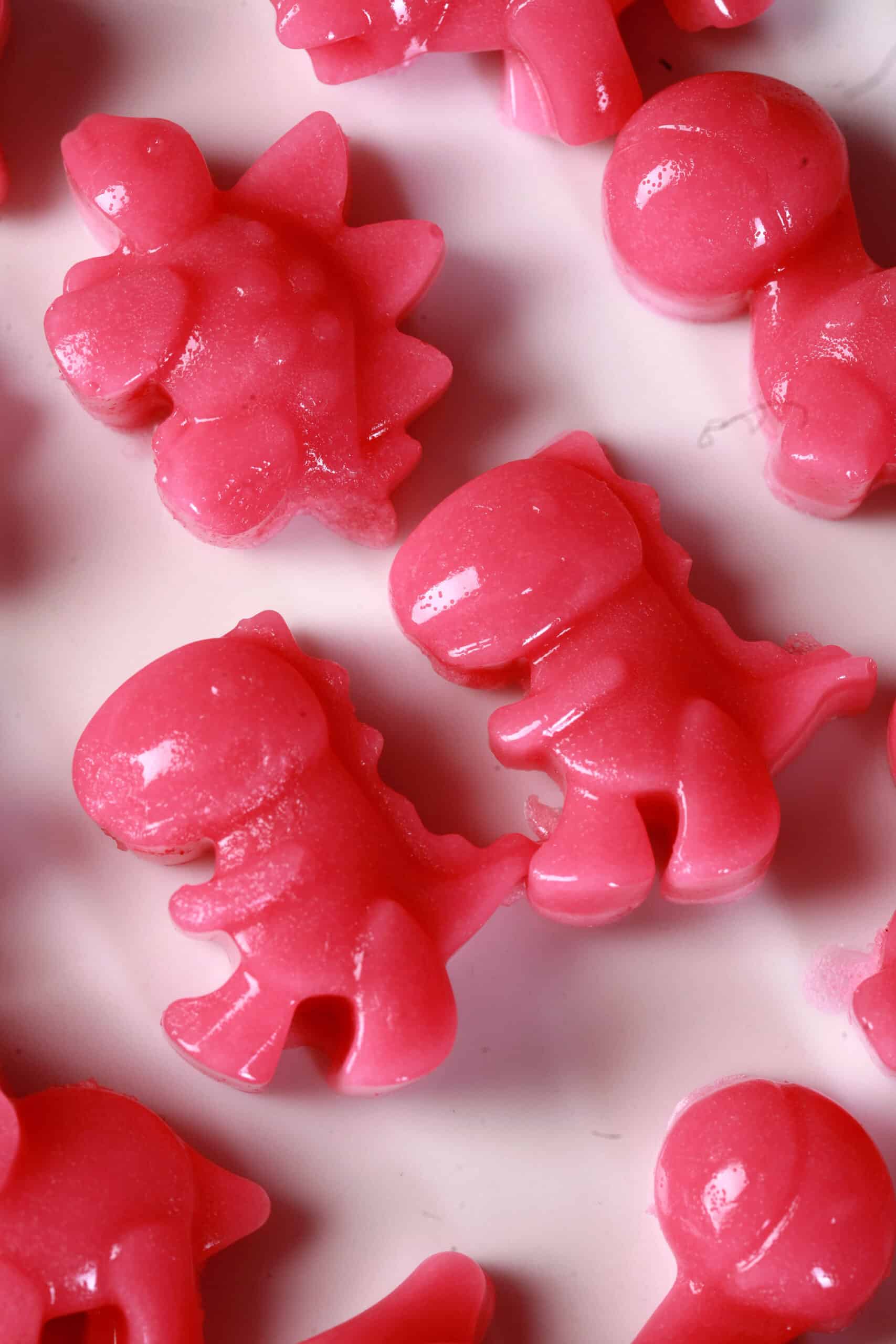Pink dinosaur shaped homemade protein keto gummies on a plate.