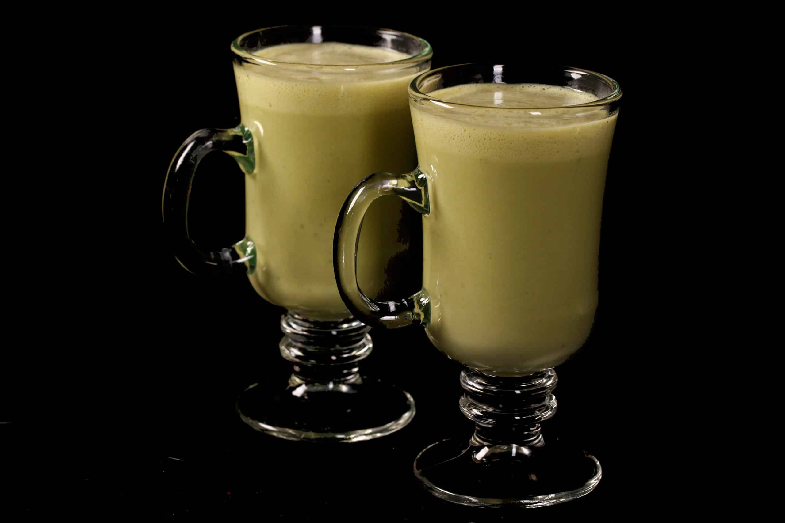 2 protein powder keto matcha lattes in glass mugs.