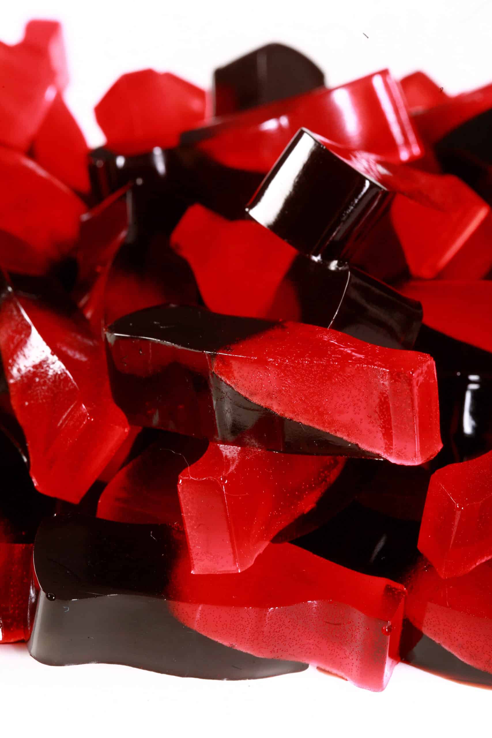 A pile of 2 colored red and brown coke bottle shaped keto sour cherry cola gummies.
