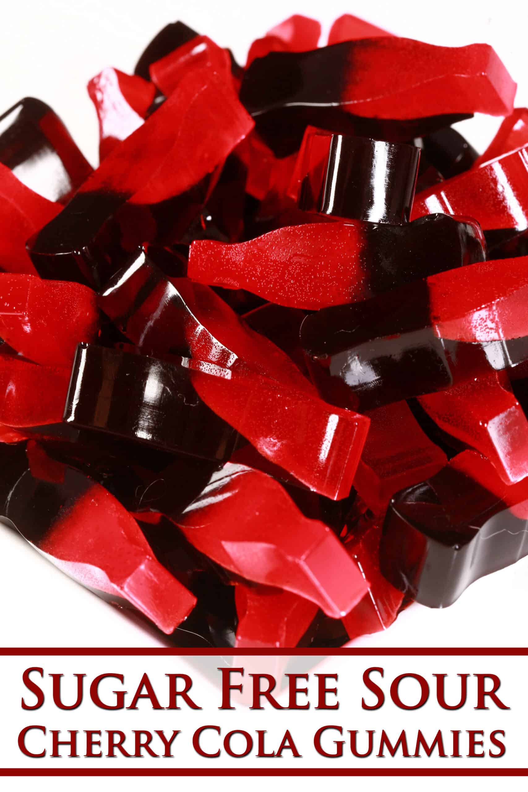 A pile of red and brown 2 coloured bottle shaped gummies.  Overlaid text says sugar free sour cherry cola gummies.