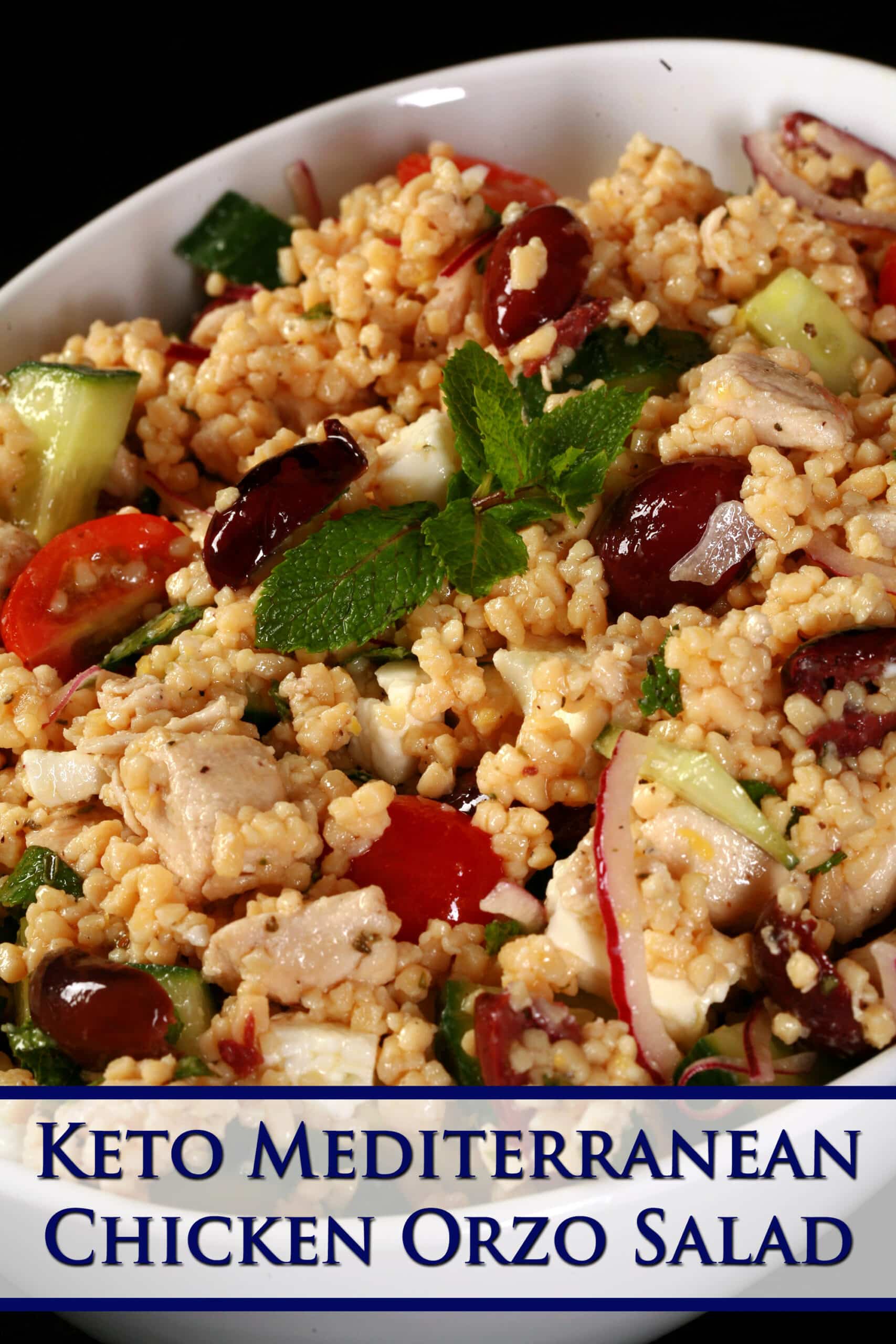 A big bowl of keto pasta salad with olives, feta, tomatoes, chicken, and mint showing. Overlaid text says keto mediterranean chicken orzo salad.