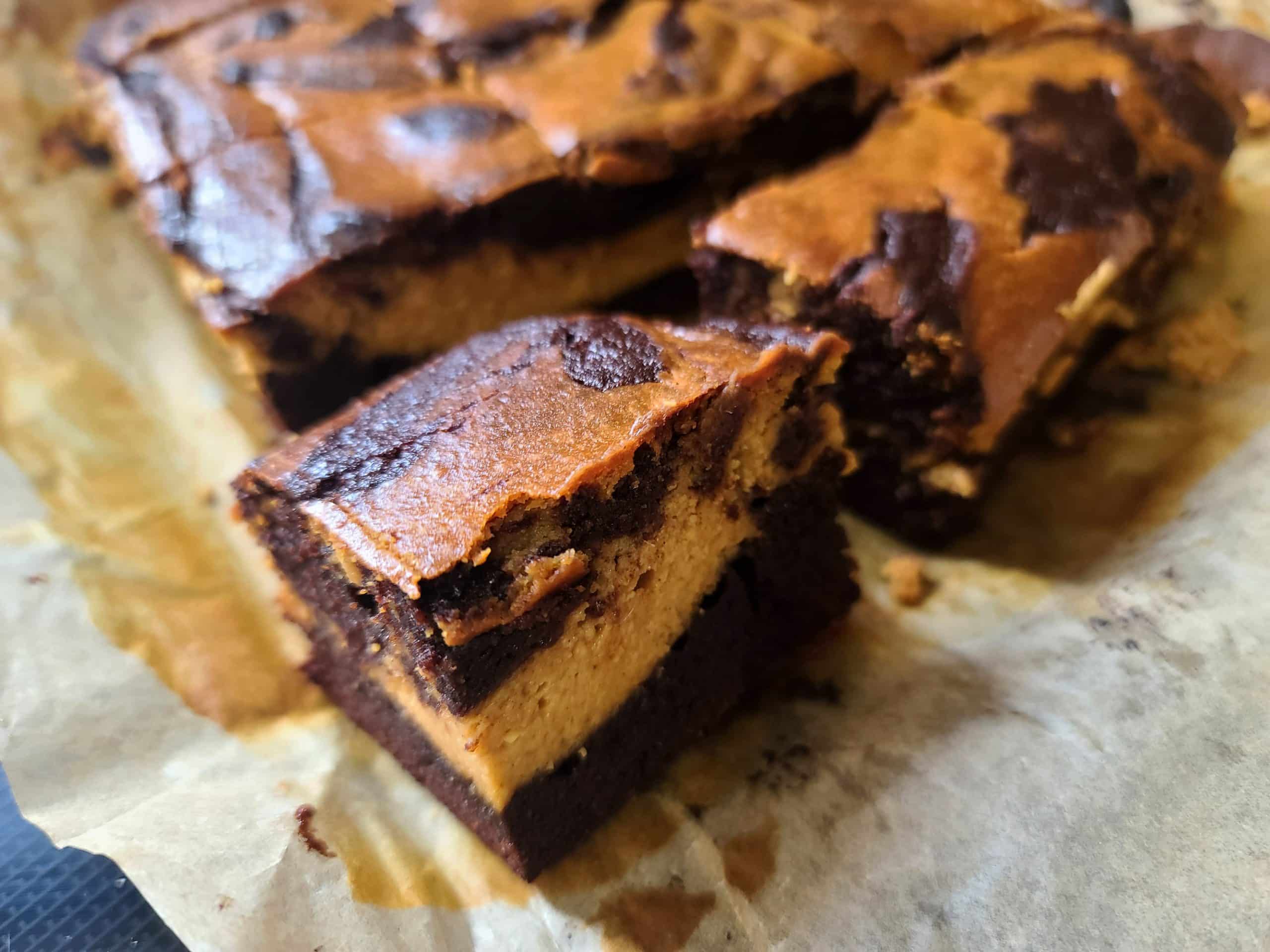 A slab of low carb pumpkin cheesecake brownies being cut into squares.