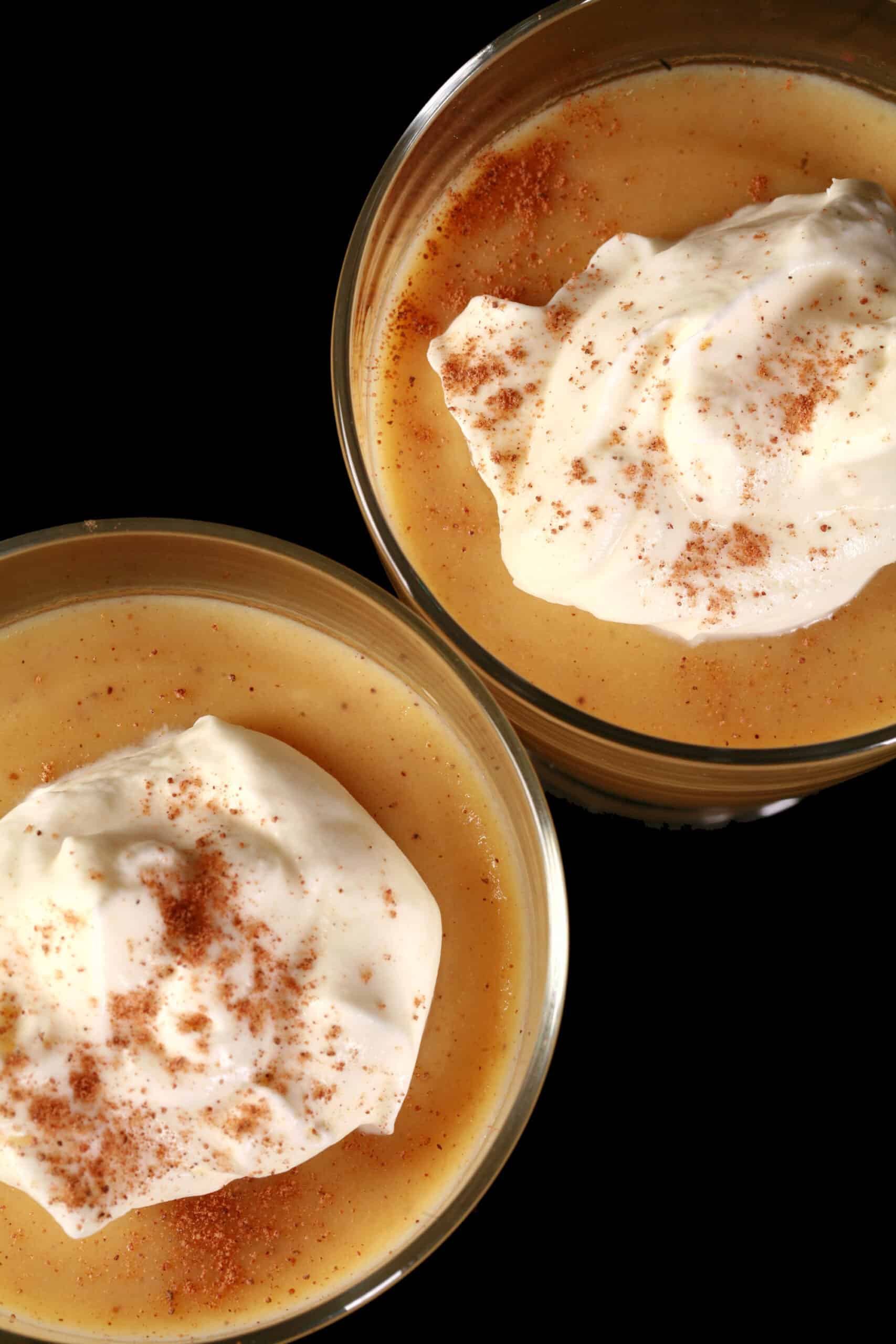 2 glasses of of low carb eggnog pudding garnished with whipped cream and nutmeg,