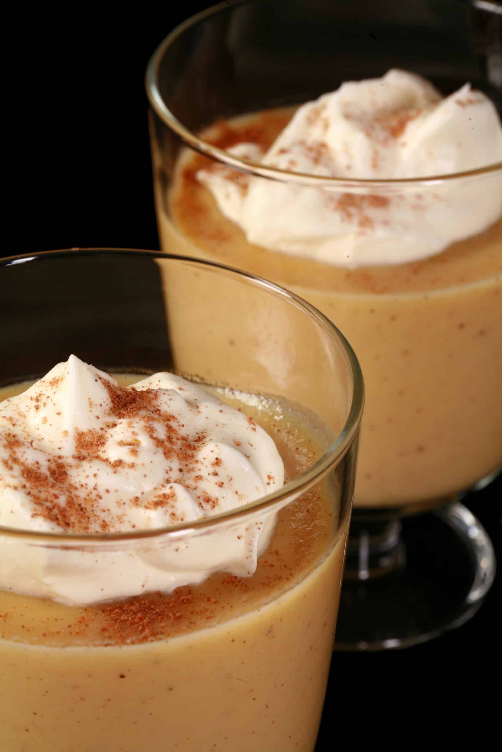 2 glasses of of keto eggnog pudding garnished with whipped cream and nutmeg,