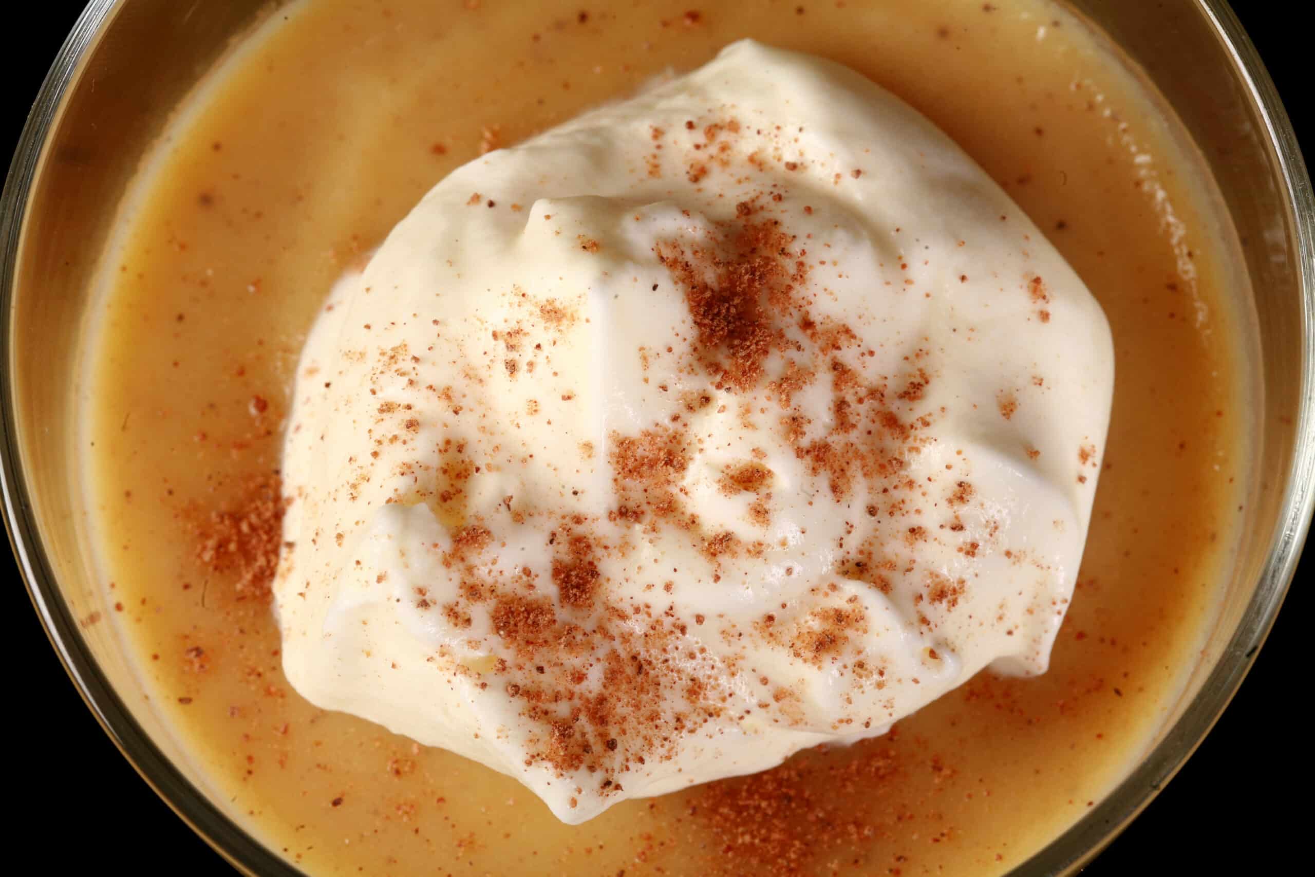 A glass of low carb eggnog pudding garnished with whipped cream and nutmeg,