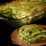 A pan of pesto chicken zucchini lasagna, with a serving on a plate in front of it.