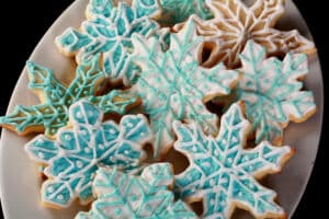 A plate of low carb sugar cookies decorated as blue and white snowflakes.