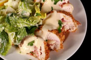 A sliced up keto chicken cordon bleu, with caesar salad on the side.