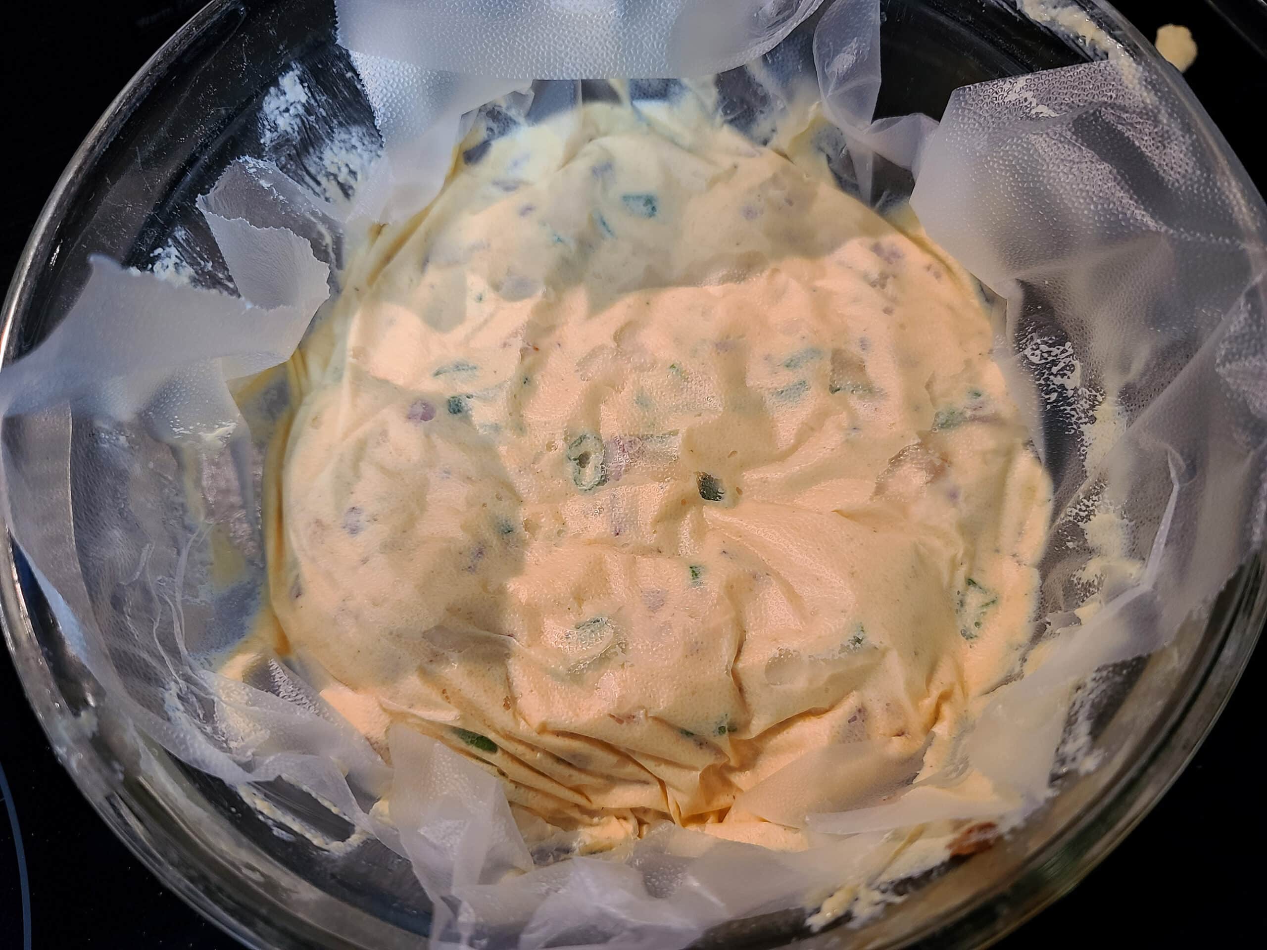 A bowl of freshly made perogy dip, covered in plastic wrap.