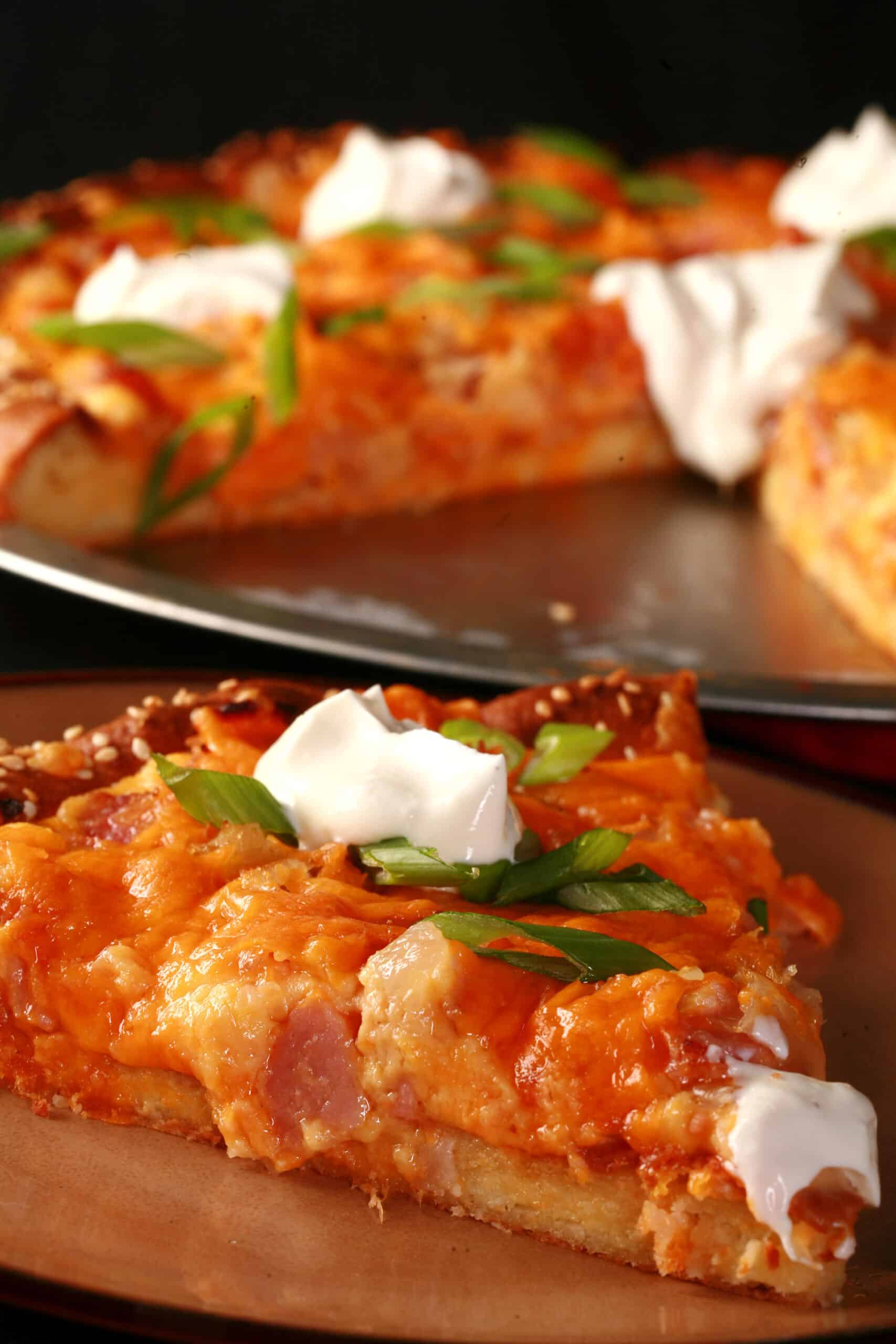 A low carb perogy pizza topped with sour cream and sliced green onions.