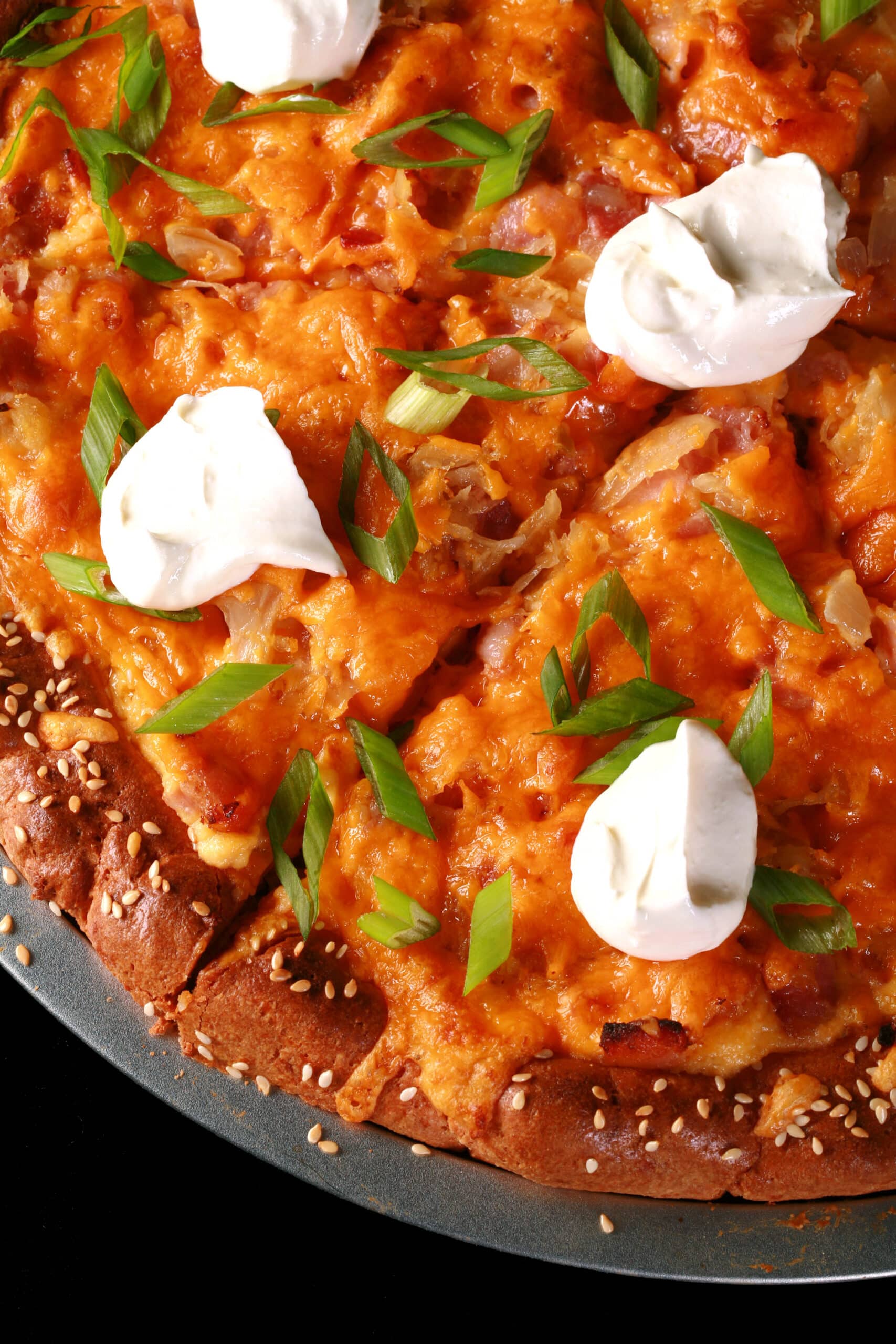 A low carb pierogi pizza topped with sour cream and sliced green onions.