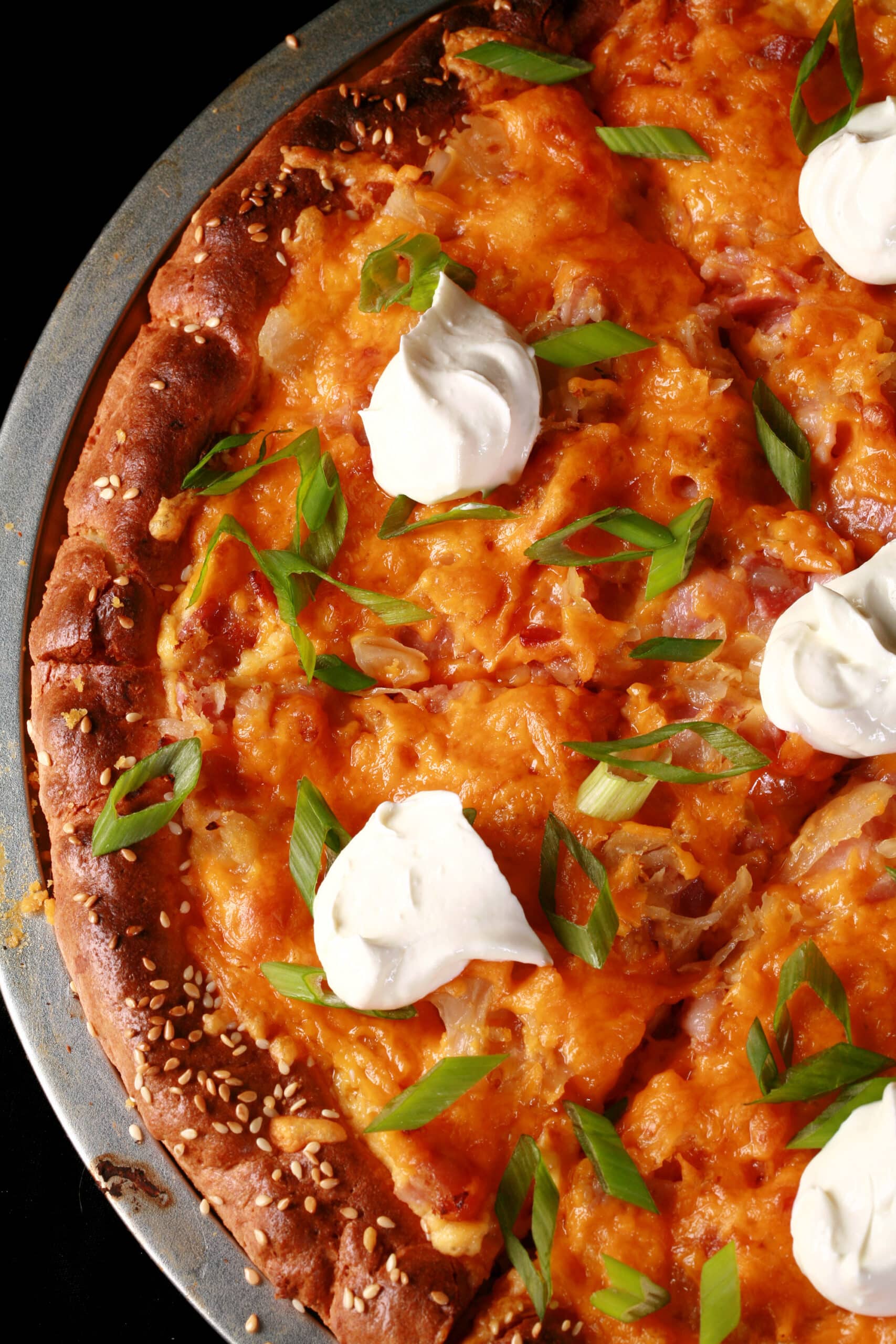 A low carb perogy pizza topped with sour cream and sliced green onions.