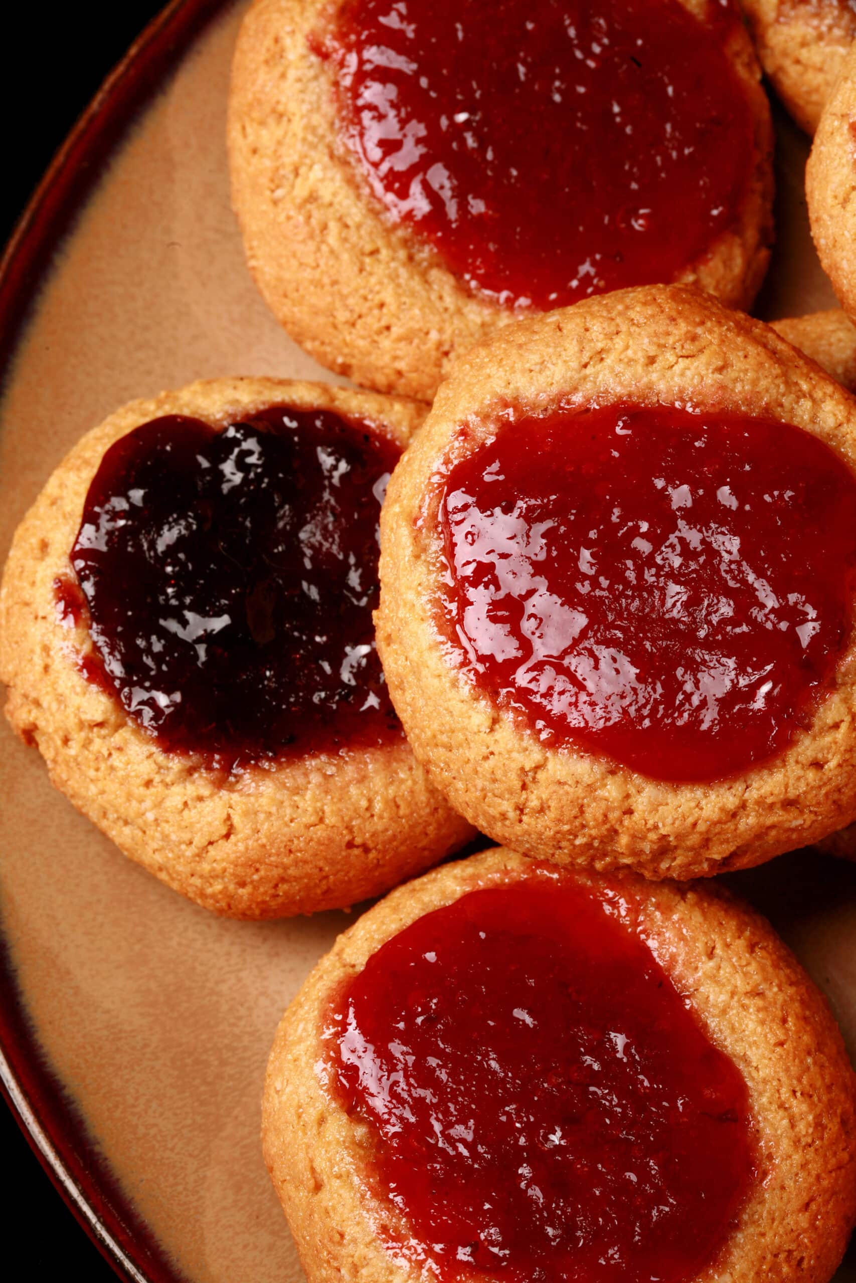 A plate of low carb peanut butter and jelly cookies, topped with sugar free blueberry and sugar free strawberry jam.