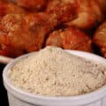 A a small bowl of Mediterranean seasoning, in front of a plate of Greek dry rub wings.