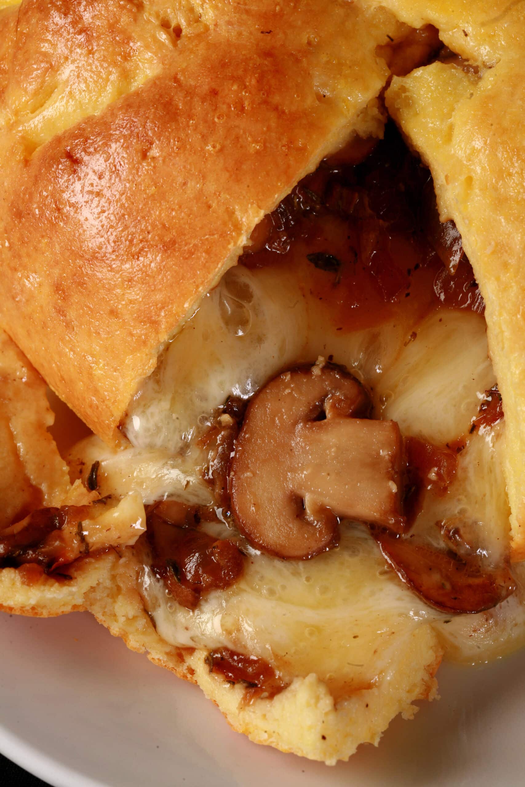 A fathead wrapped keto brie en croute, cut open to show melted cheese and sauteed mushrooms pouring out.