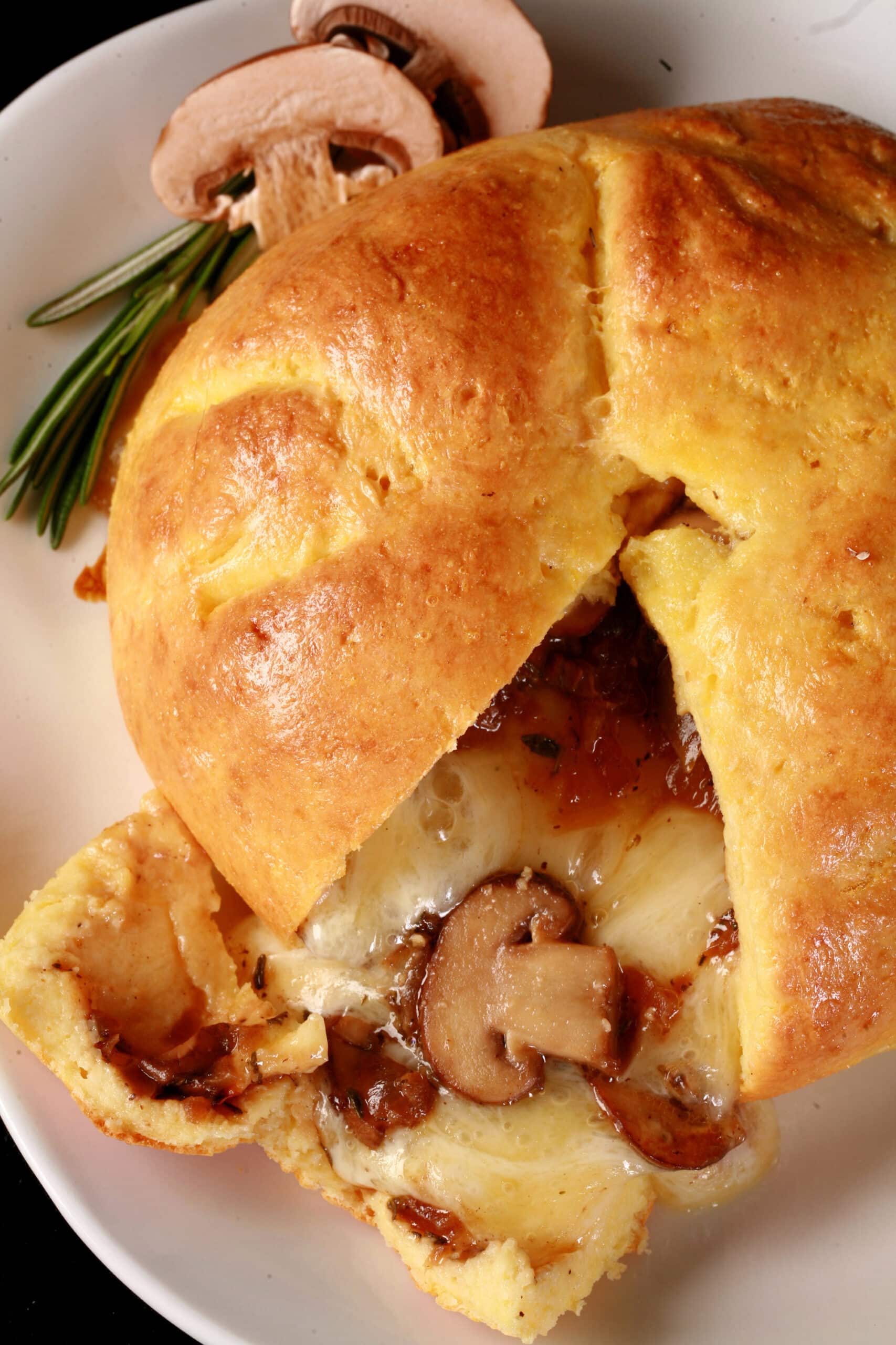 A fathead wrapped low carb brie en croute, cut open to show melted cheese and sauteed mushrooms pouring out.