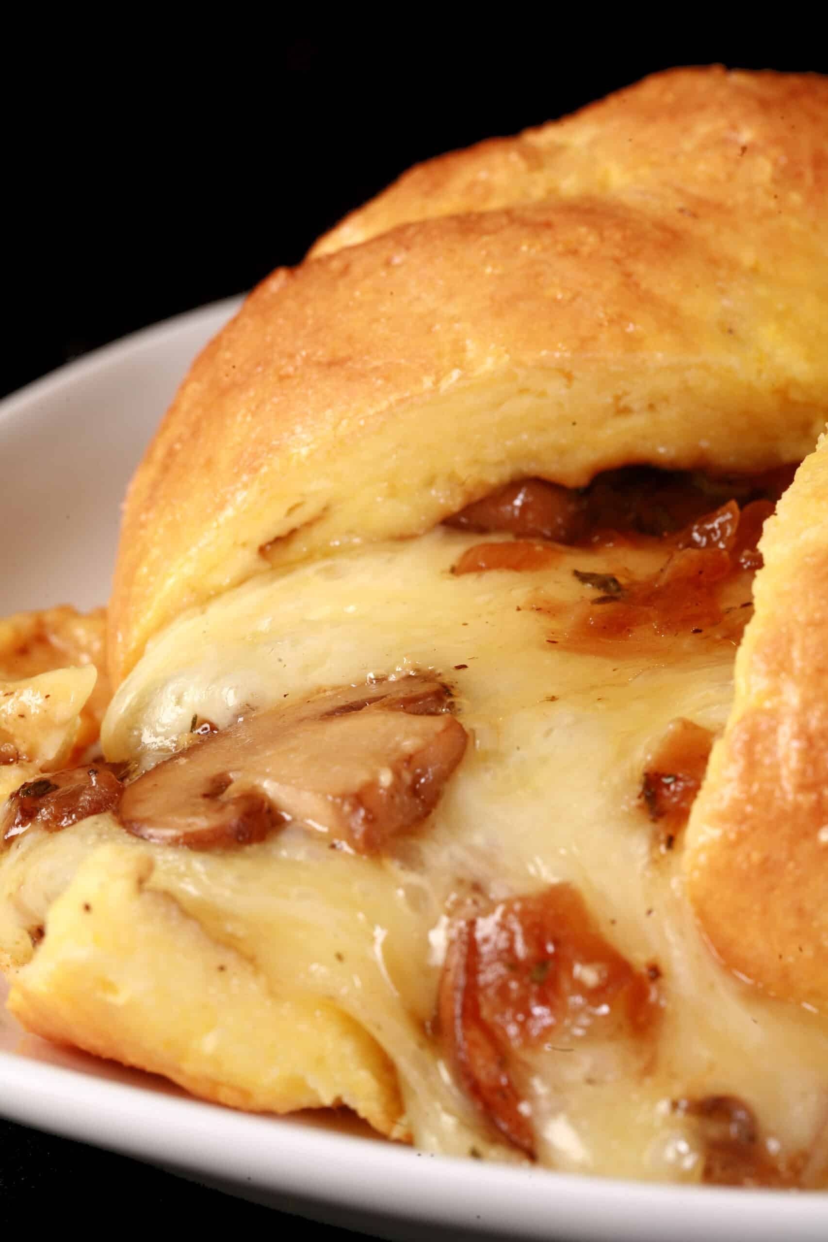 A fathead wrapped keto brie en croute, cut open to show melted cheese and sauteed mushrooms pouring out.