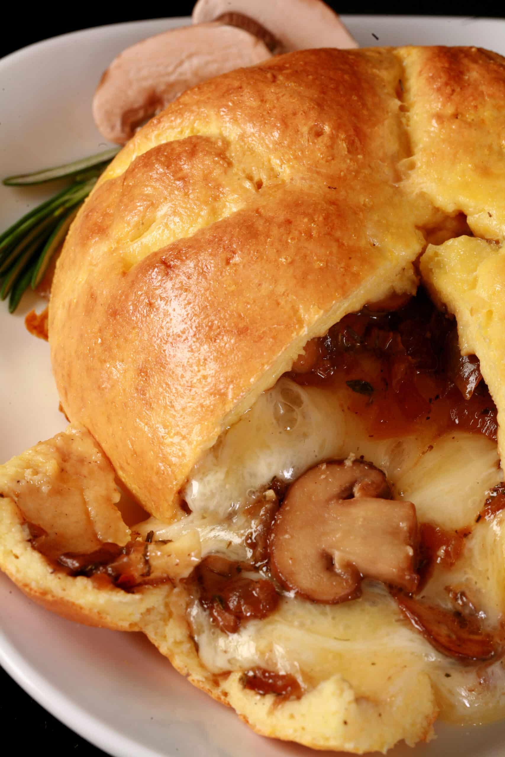 A fathead wrapped low carb brie en croute, cut open to show melted cheese and sauteed mushrooms pouring out.