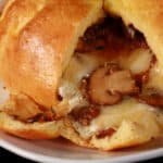 A fathead wrapped keto brie en croute, cut open to show melted cheese and sauteed mushrooms pouring out.