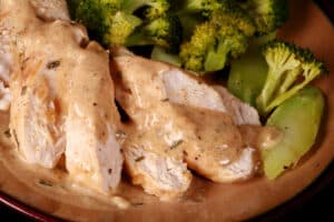 Slices of chicken with creamy mustard sauce and roasted broccoli.