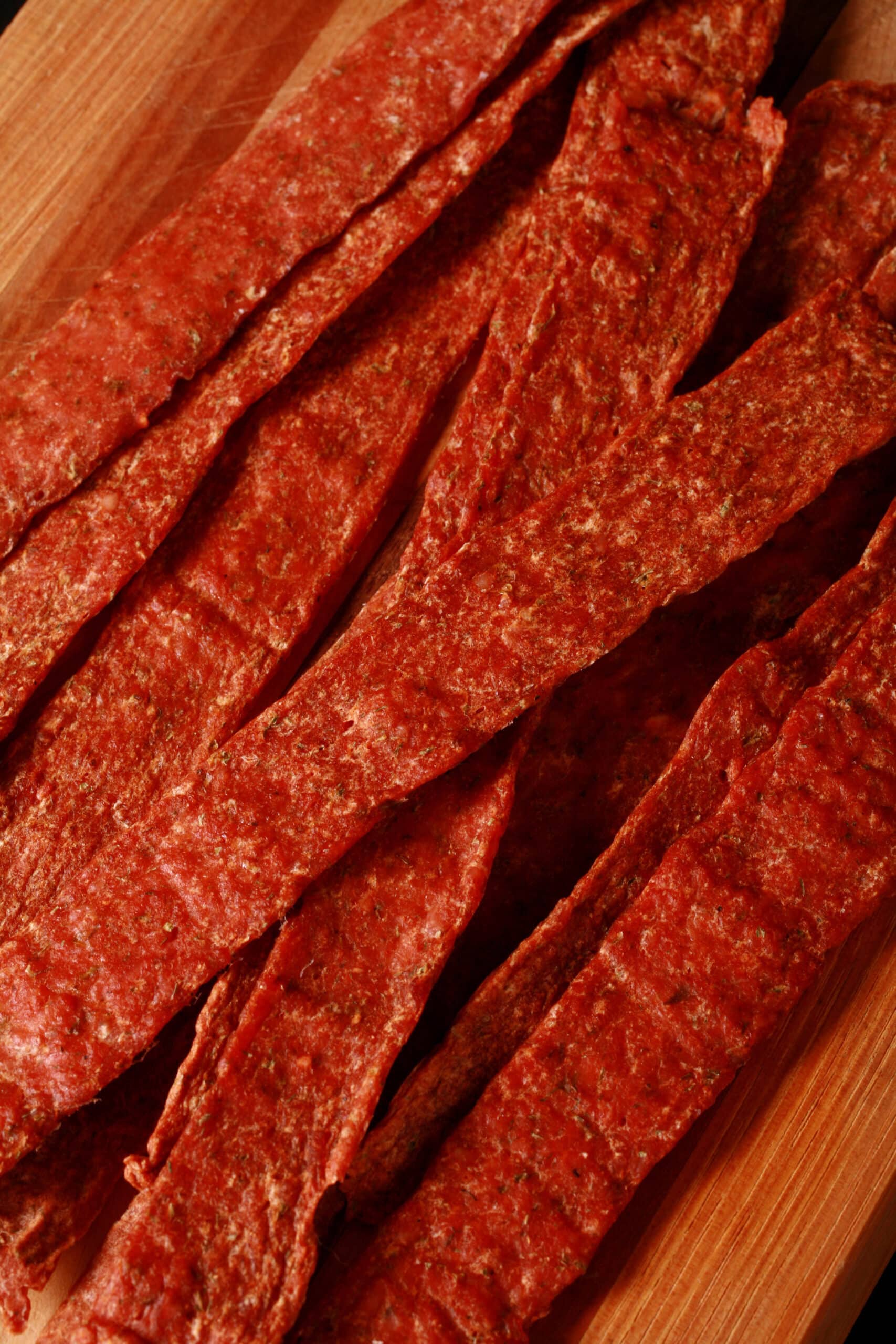 Several strips of buffalo chicken jerky on a cutting board.