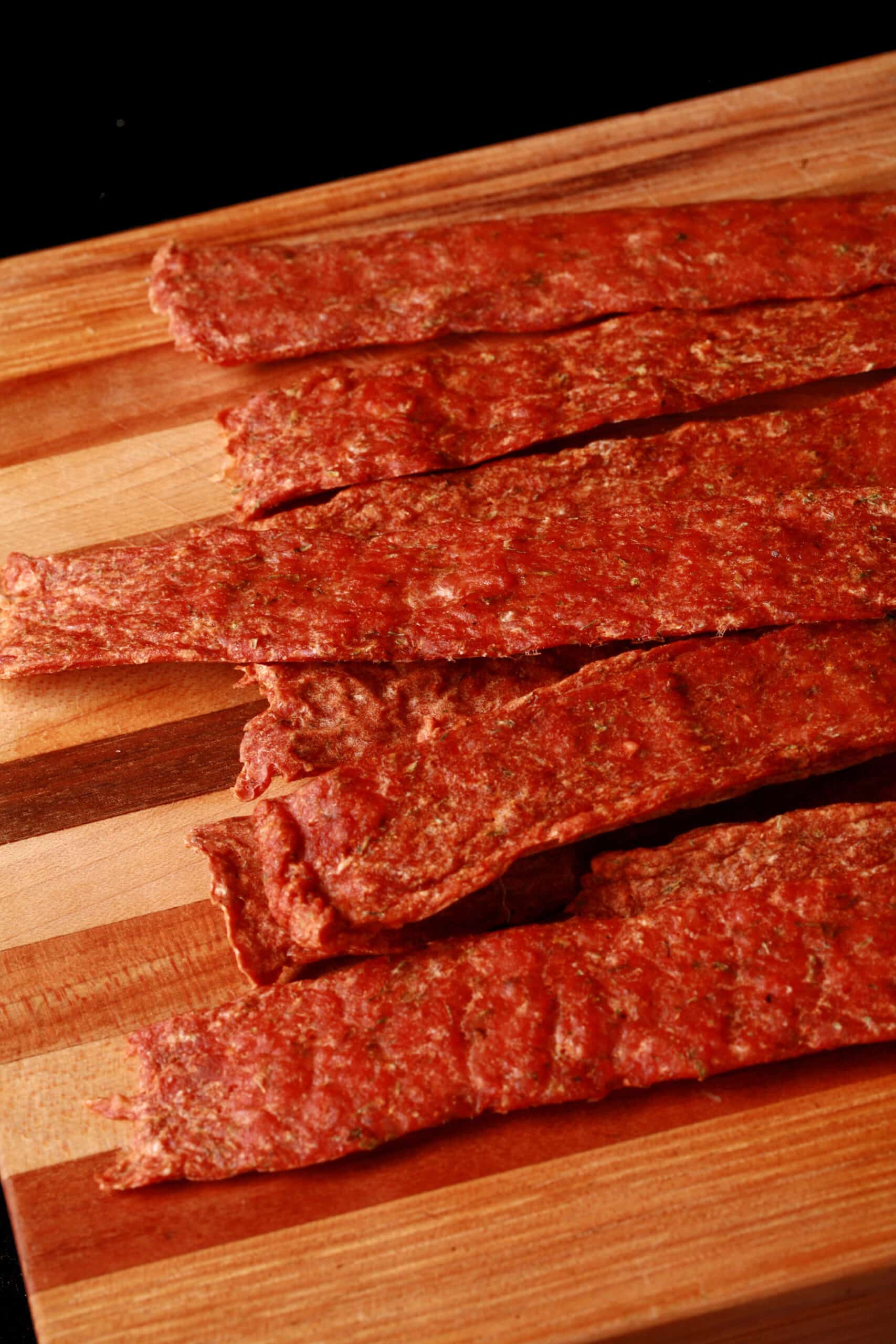 Several strips of buffalo wing chicken jerky on a cutting board.