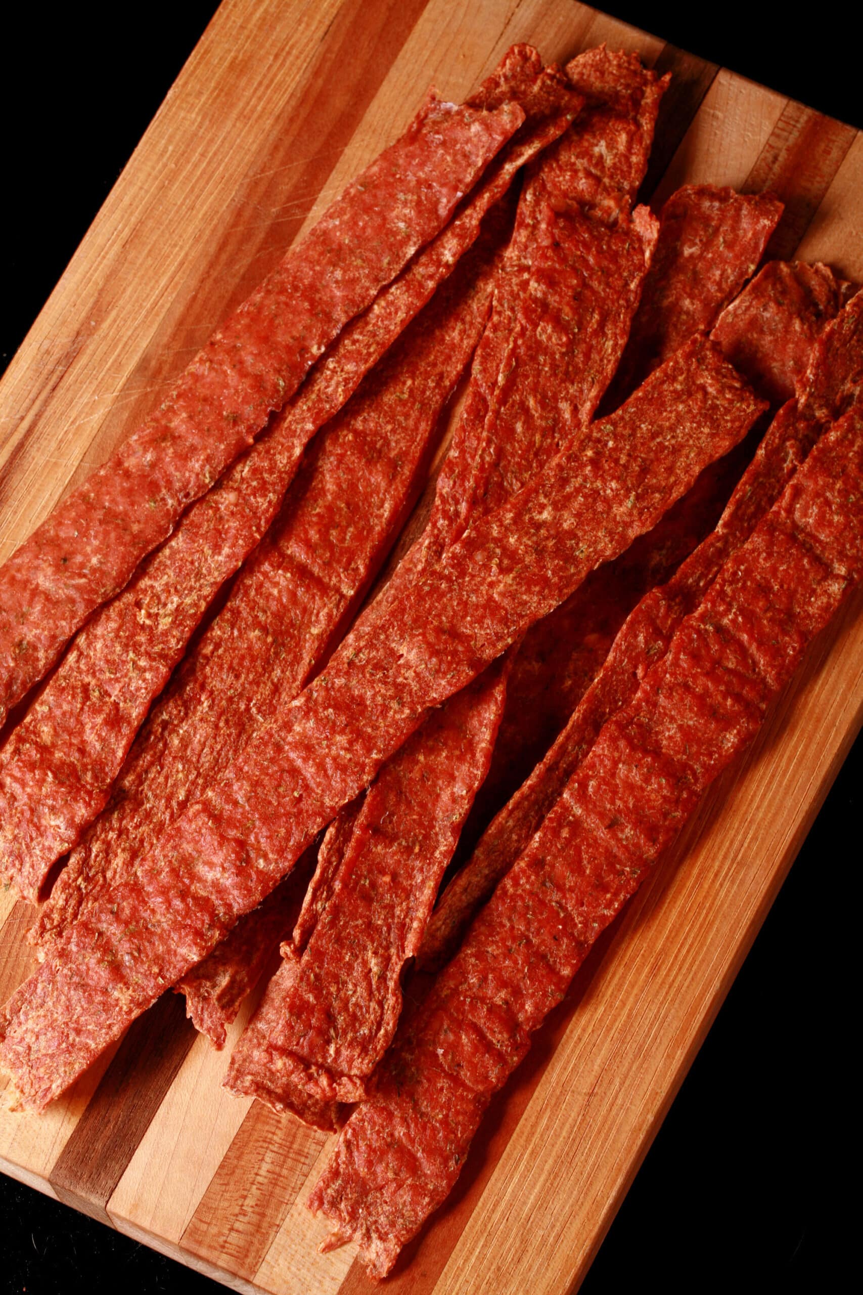 Several strips of buffalo chicken jerky on a cutting board.