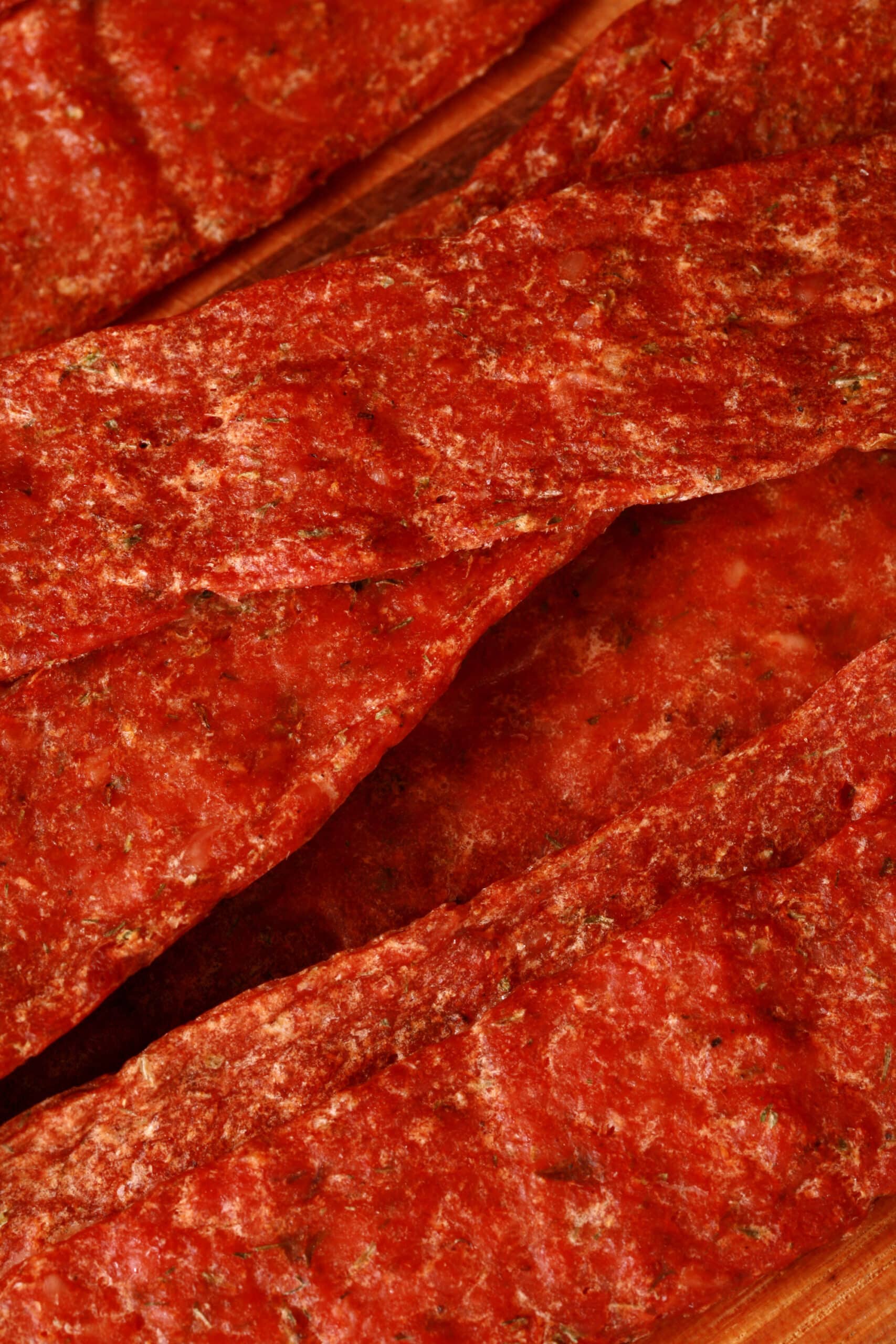 Several strips of buffalo wing chicken jerky on a cutting board.