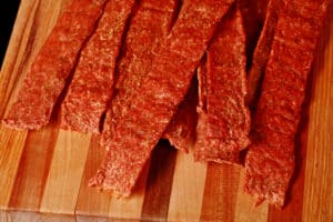 Several strips of buffalo chicken jerky on a cutting board.