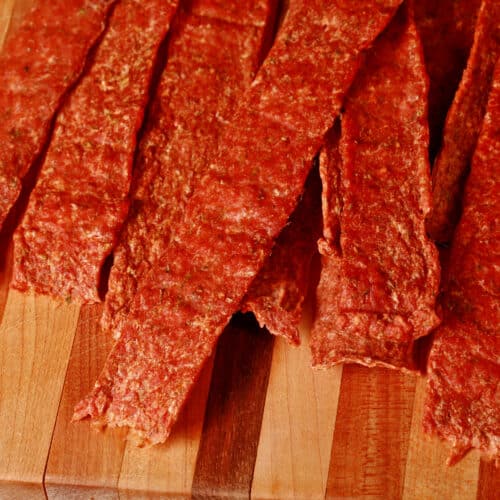 Several strips of buffalo chicken jerky on a cutting board.