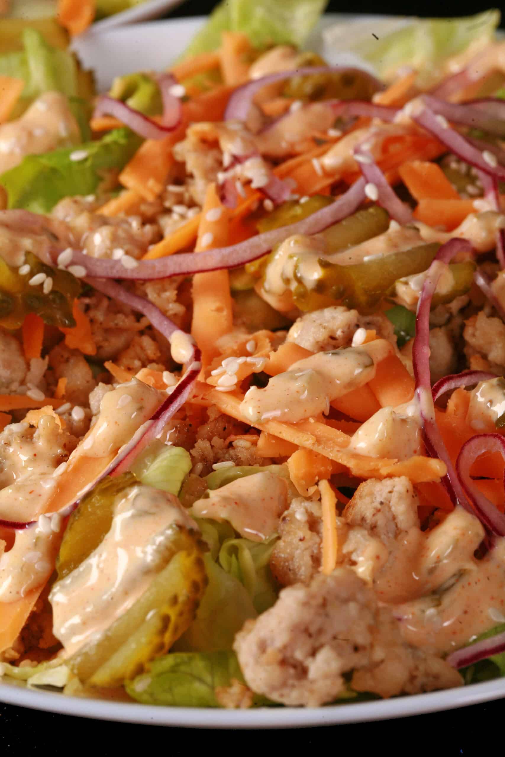 A bowl of keto big mac salad, with iceberg lettuce, ground beef, cheese, pickles, onions, and low carb big mac sauce.