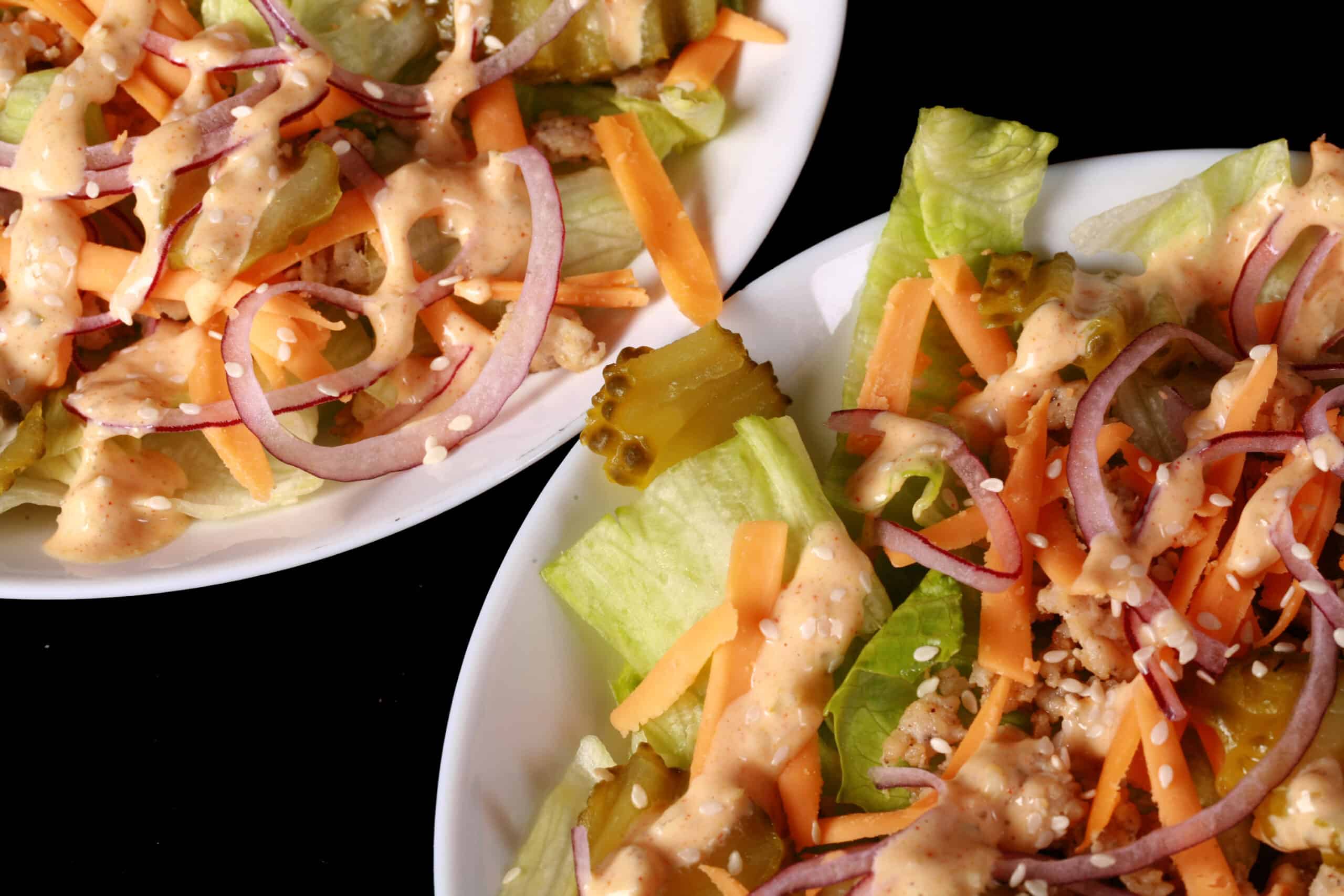 2 bowls of low carb big mac salad, with iceberg lettuce, ground beef, cheese, pickles, onions, and keto big mac sauce.