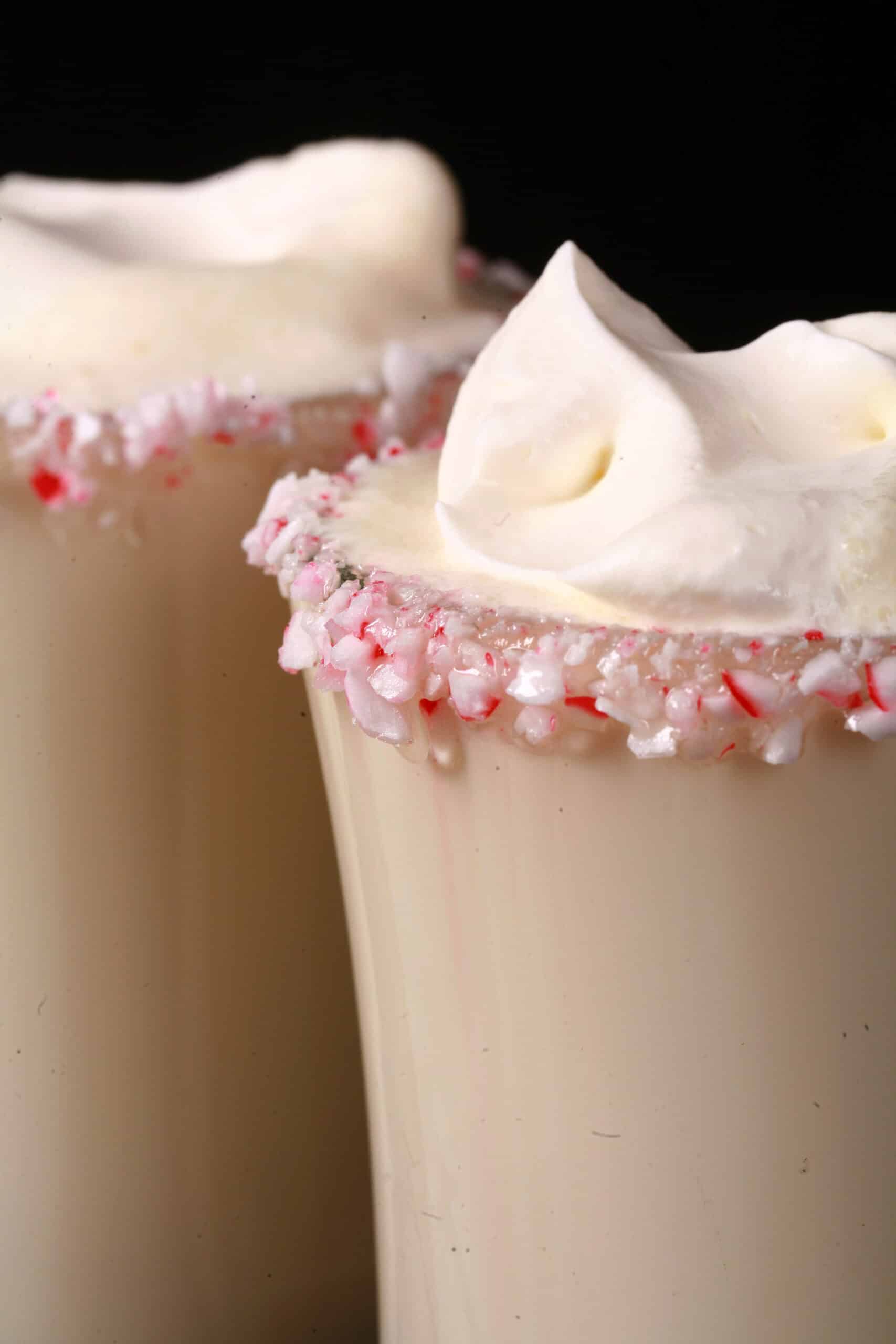 2 mugs of sugar free white hot chocolate with rims of sugar free peppermint candy, and topped with whipped cream.