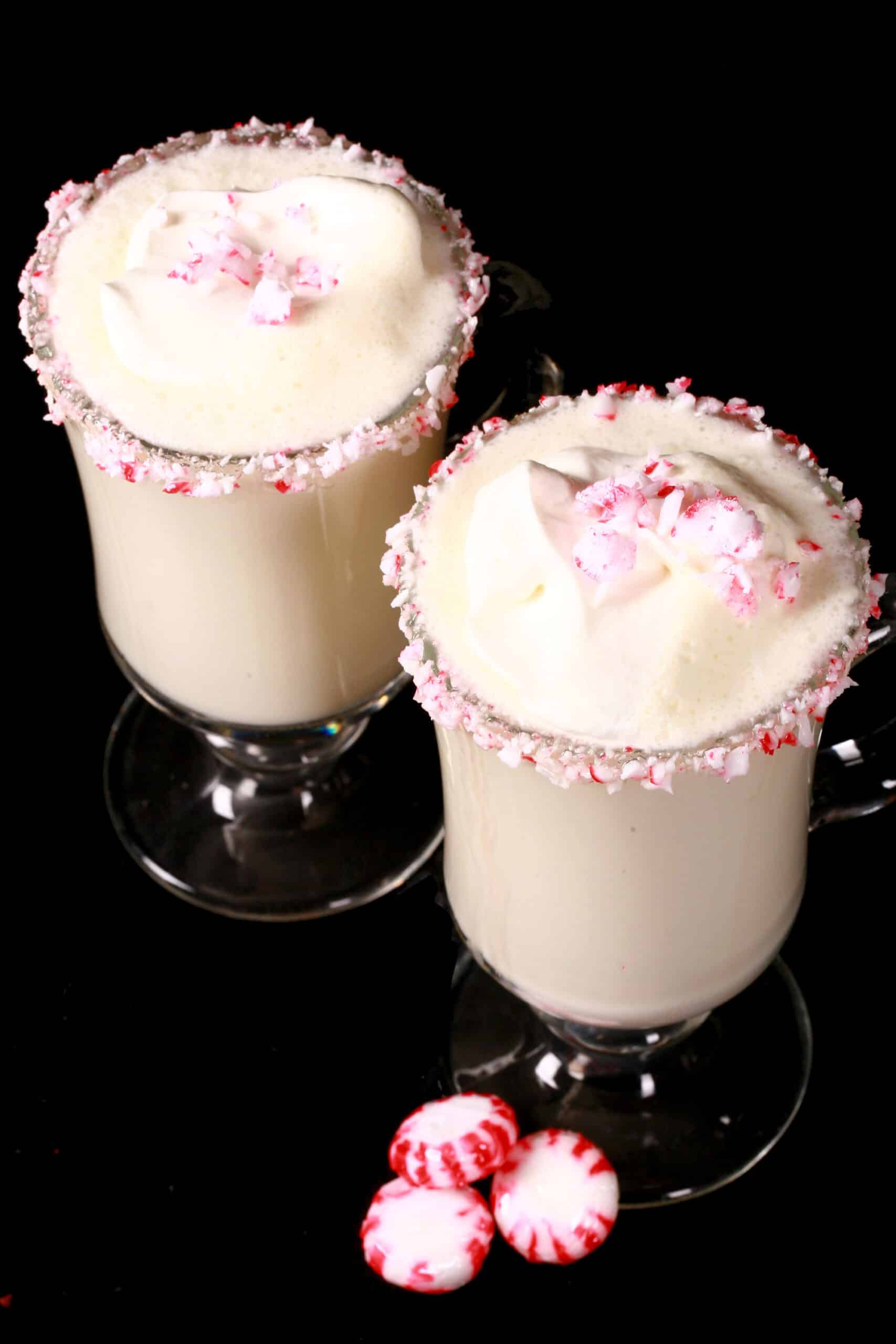 2 mugs of sugar free white hot chocolate with rims of sugar free peppermint candy, and topped with whipped cream.