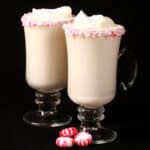 2 mugs of low carb white hot chocolate with rims of sugar free peppermint candy, and topped with whipped cream.