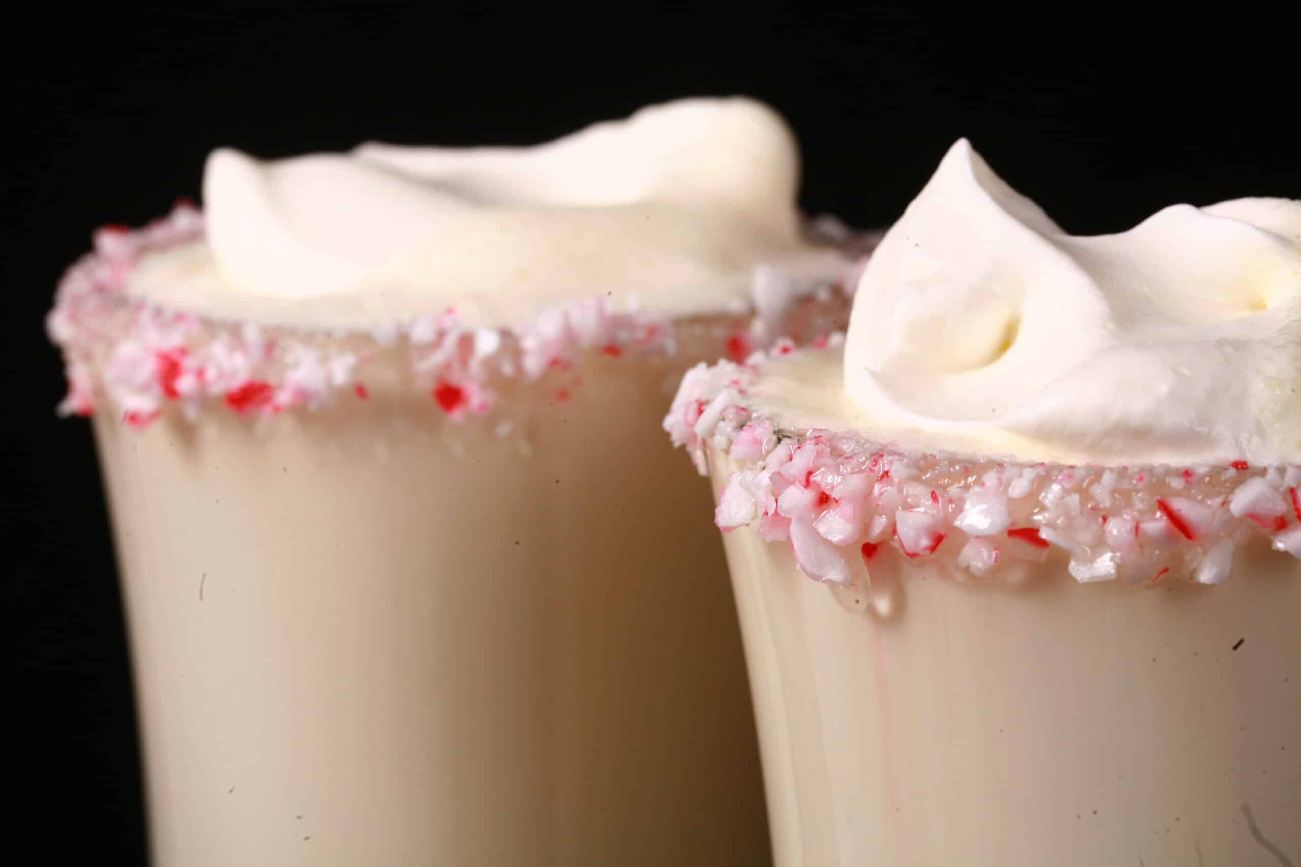 2 mugs of sugar free white hot chocolate with rims of sugar free peppermint candy, and topped with whipped cream.