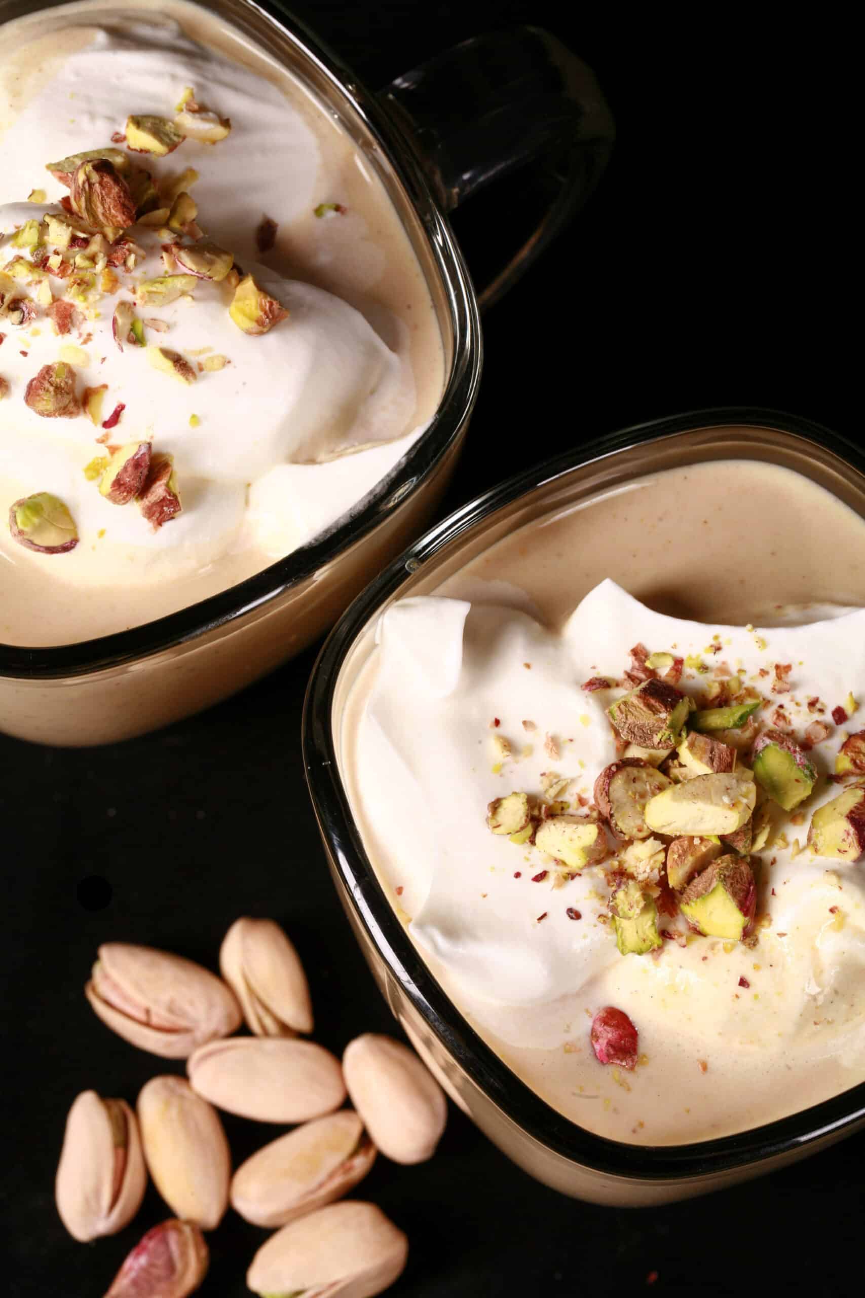 2 mugs of sugar free pistachio white hot chocolate topped with whipped cream and chopped pistachios.